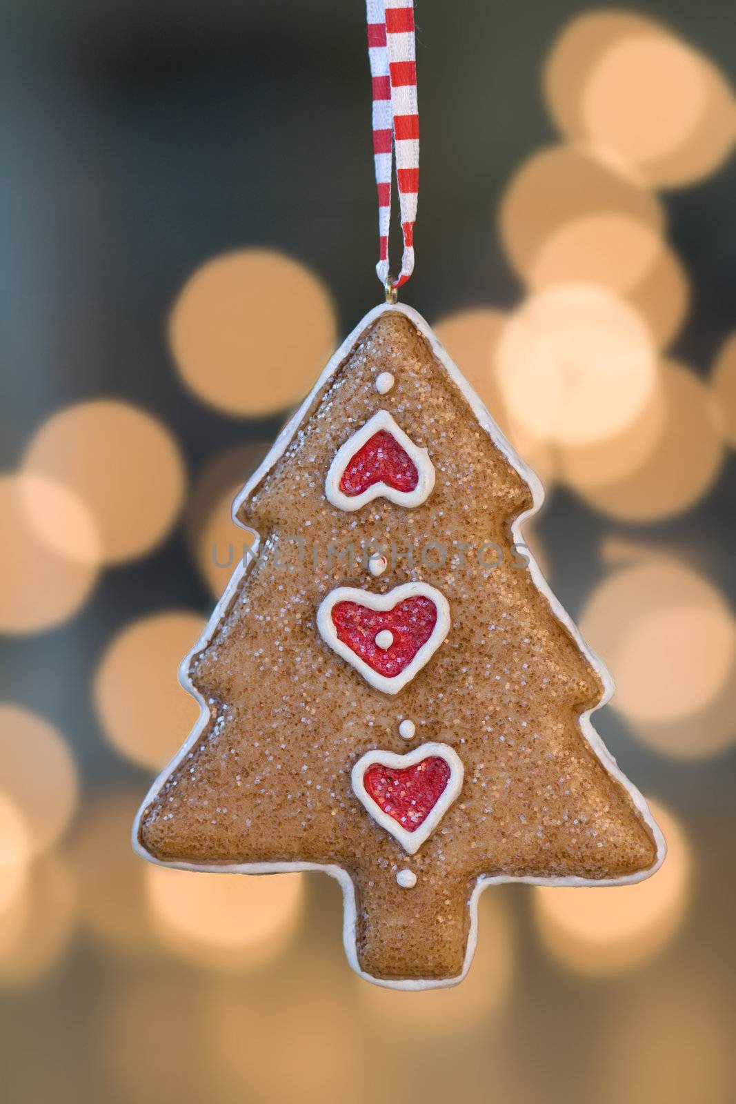 Christmas tree ornament hangs in front of de-focused christmas lights