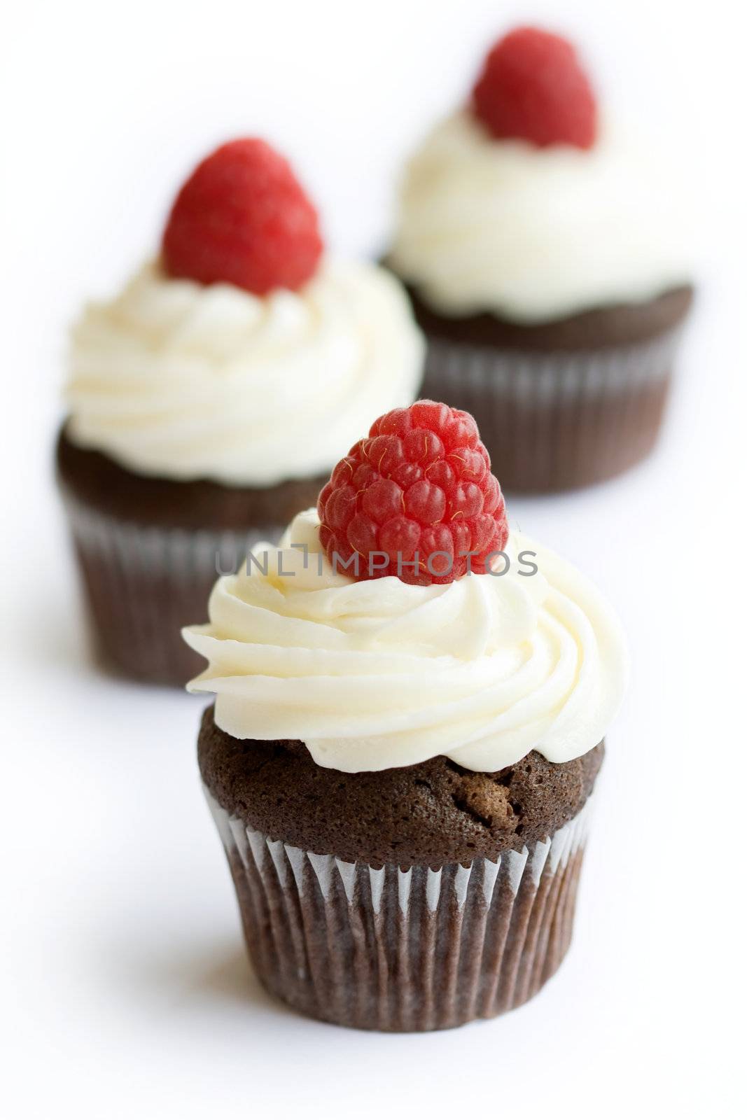 Chocolate cupcakes decorated with fresh cream and raspberries