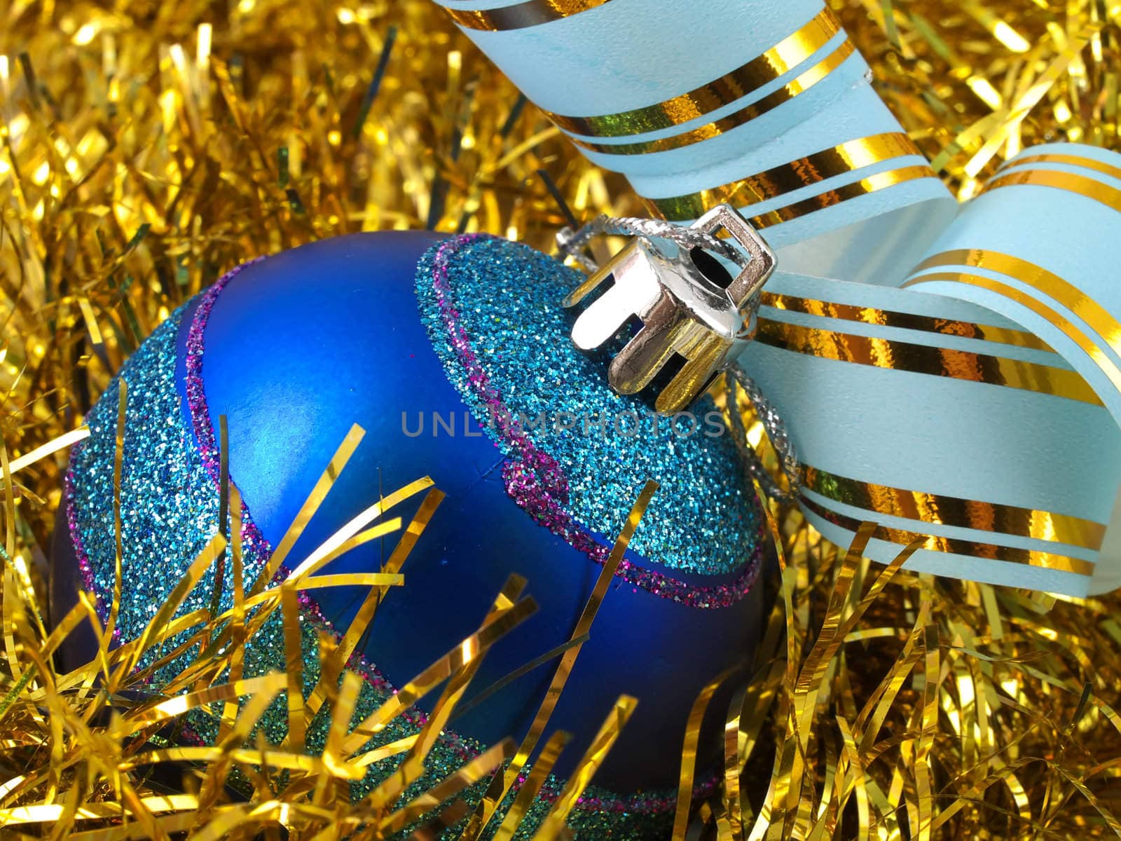 Christmas blue ornaments and colorfull  ribbon on background of gold tinselbackground