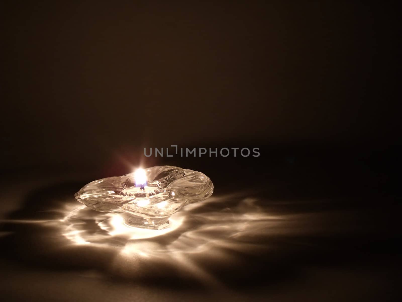 Single flame on a flower candle glowing in the night