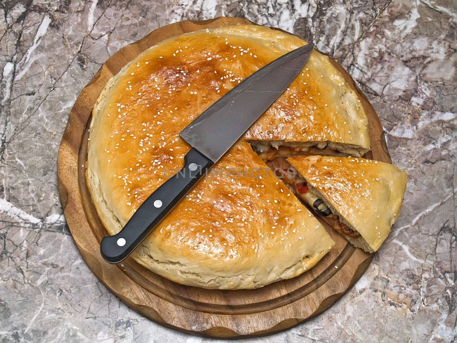 Italian staff. The closed pizza with the cut off slice on wooden kittchen board