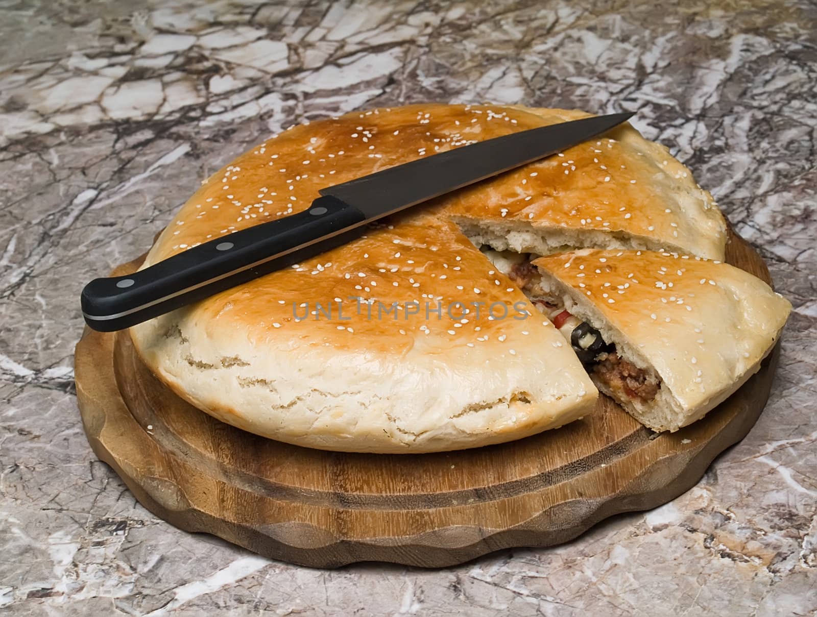 Italian staff. The closed pizza with the cut off slice on wooden kittchen board