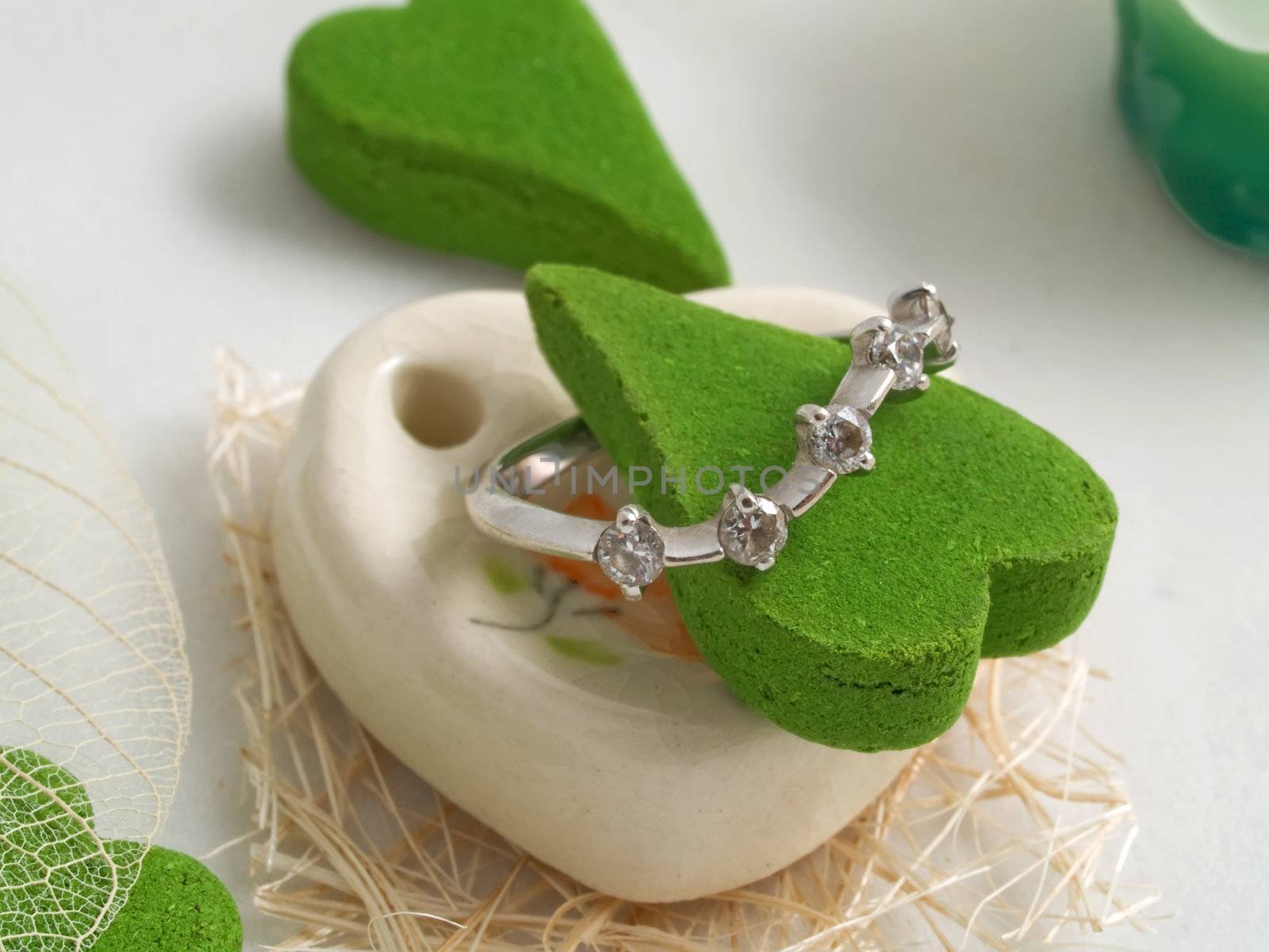Gift a set of aromas green color in the form of heart with diamond ring isolated on white