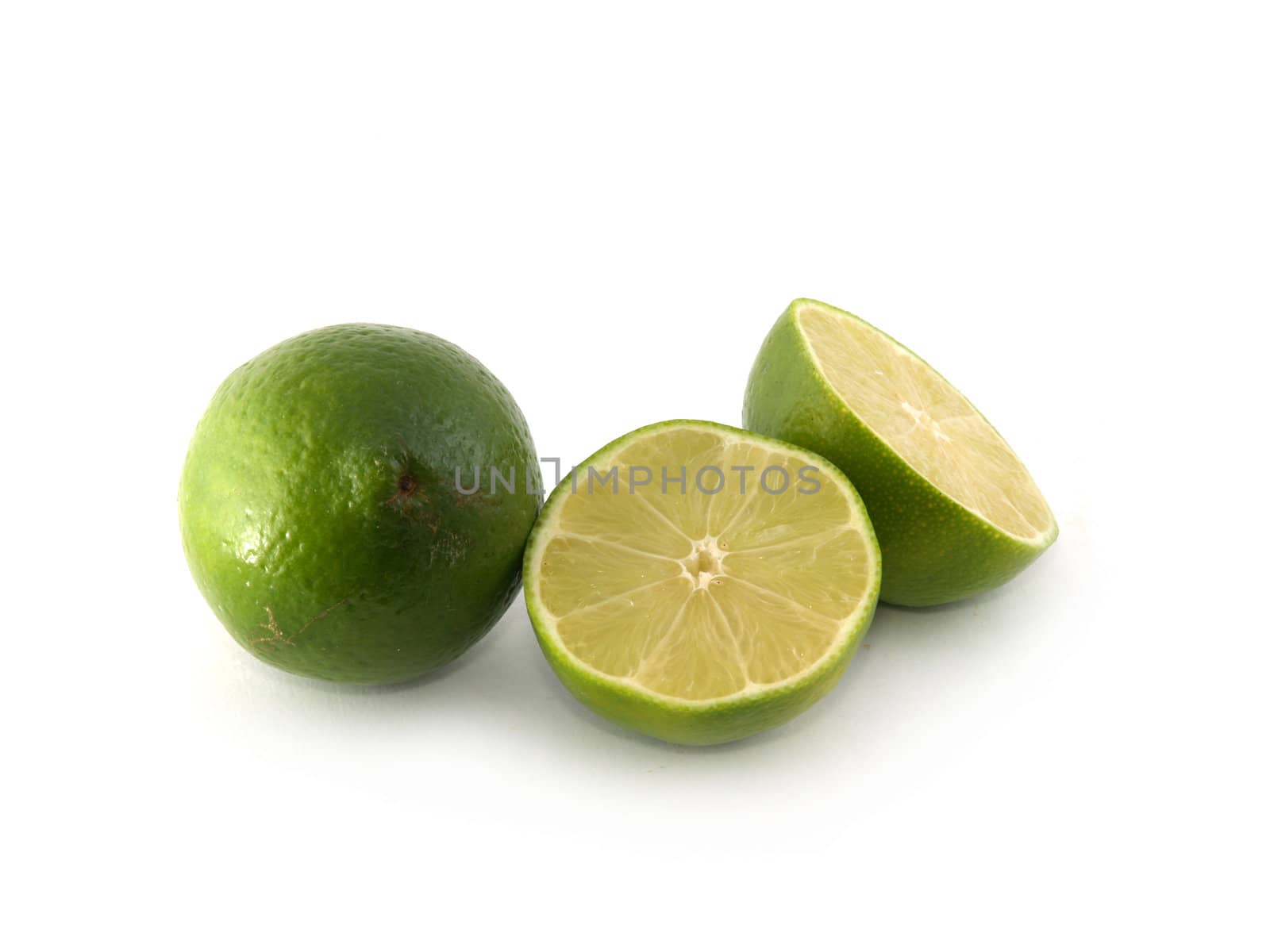 One green lime and two halves liyng on the white background