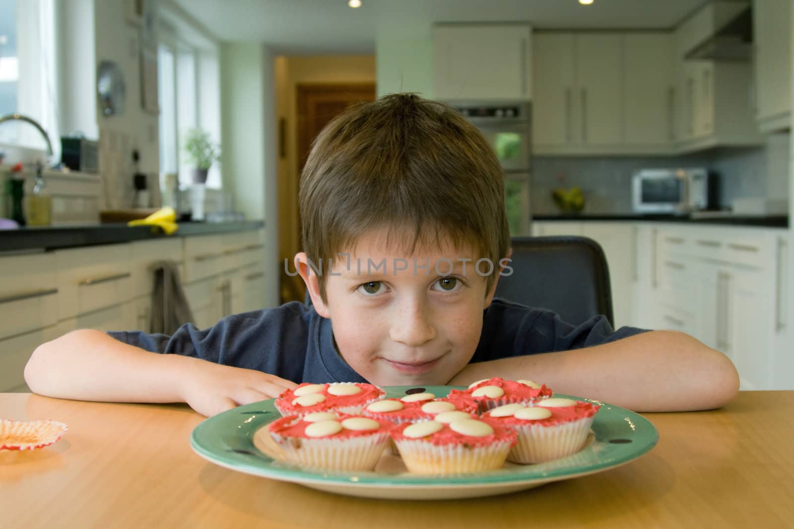 Boy with cupcakes and a mischevious grin