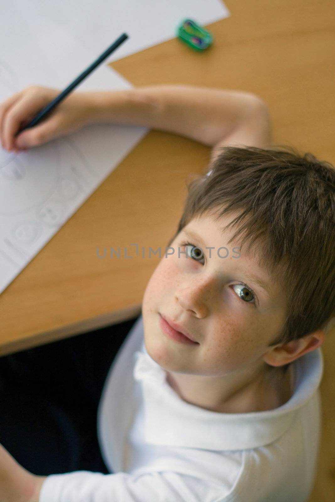 Boy at a table doing homework/drawing, high angle view