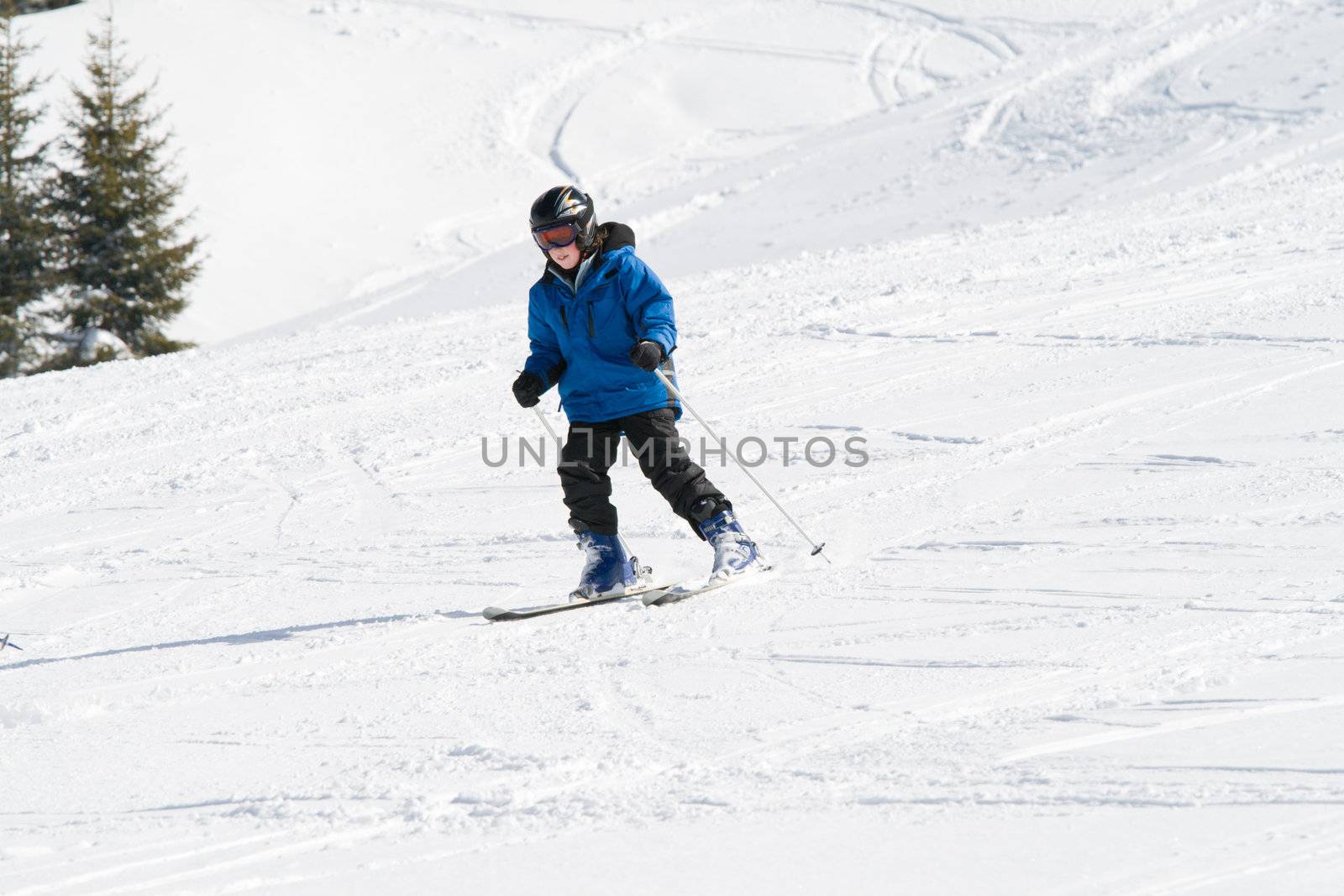 Boy skiing down a snowy slope on a sunny day