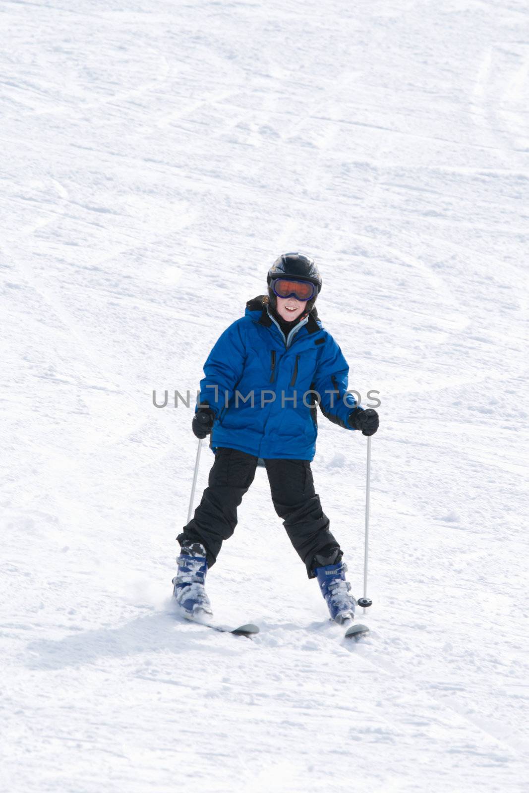 Smiling boy on skis at bottom of ski slope