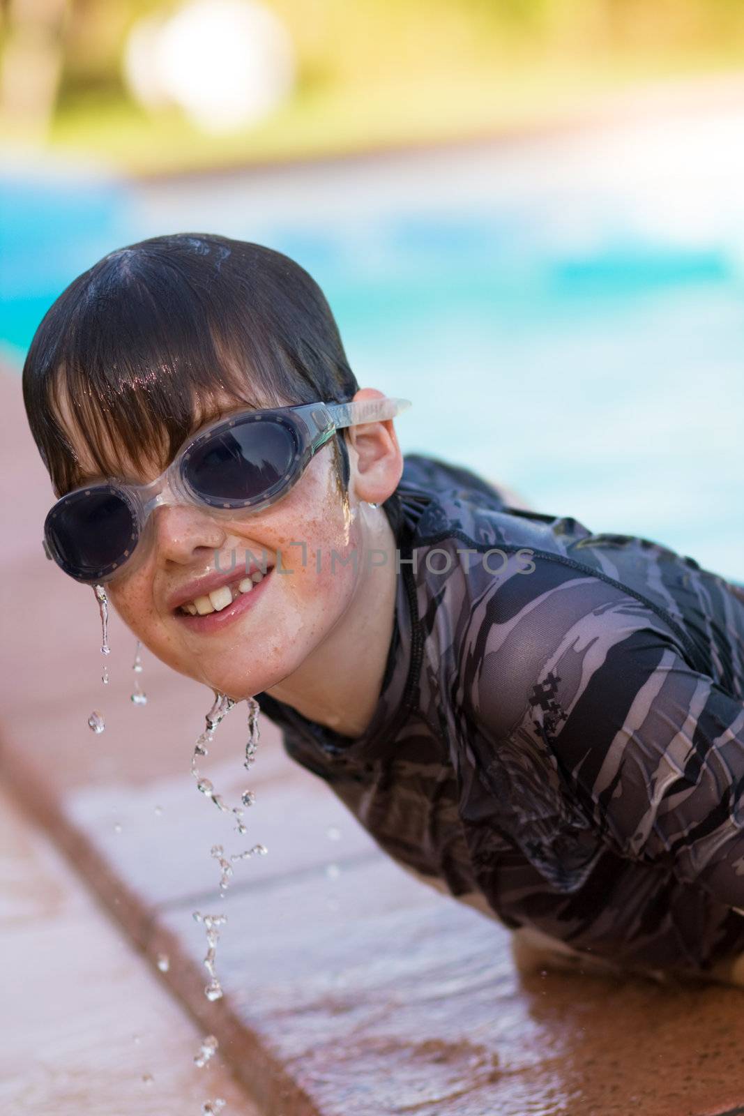 Boy wearing goggles emerges from swimming pool