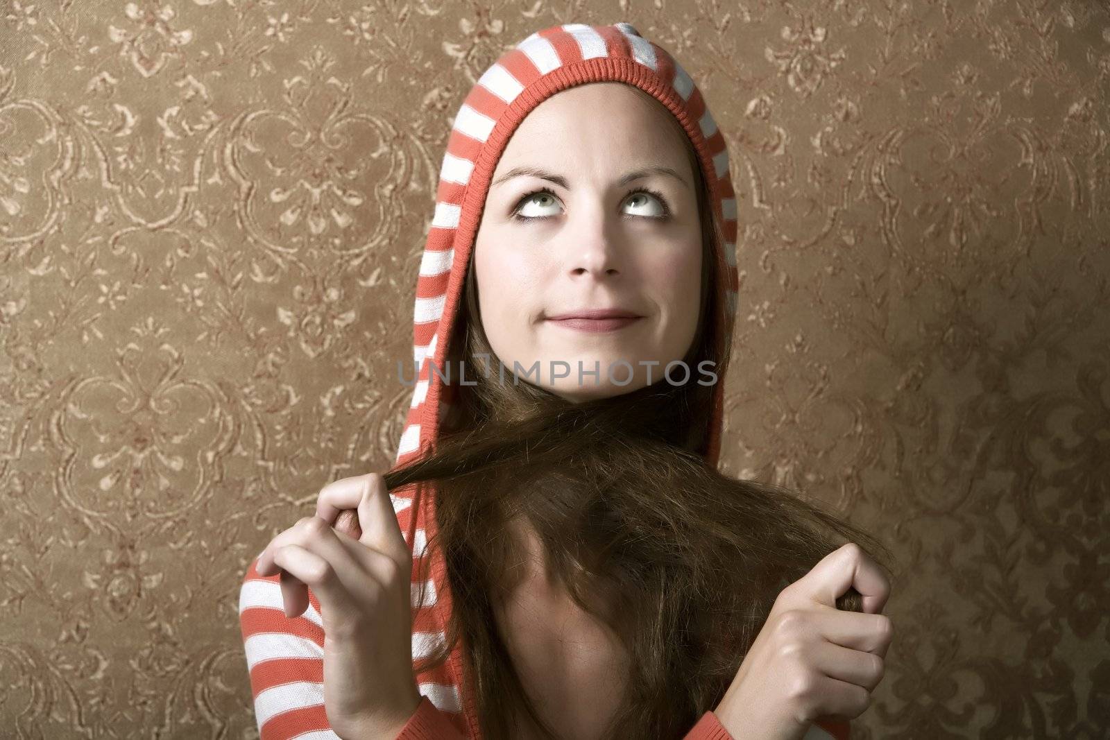 Young Woman in a Hooded Sweater Pulling on the Ends of Her Hair