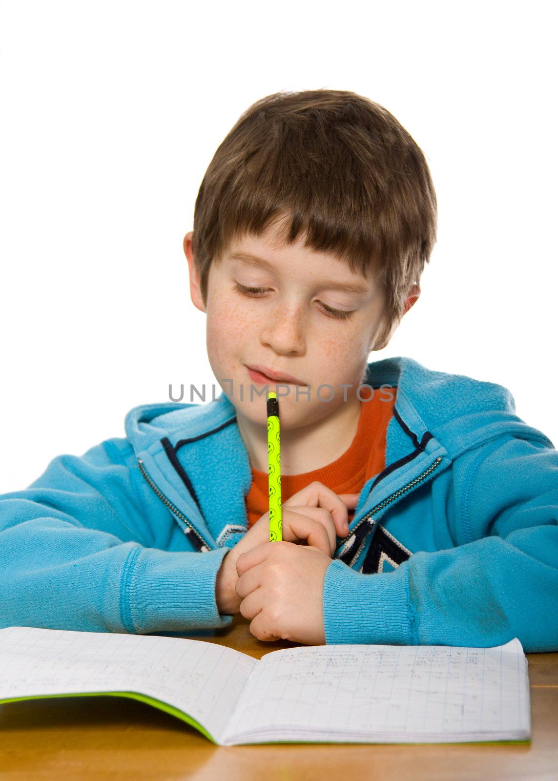 Young boy frowning over his homework, against a white background