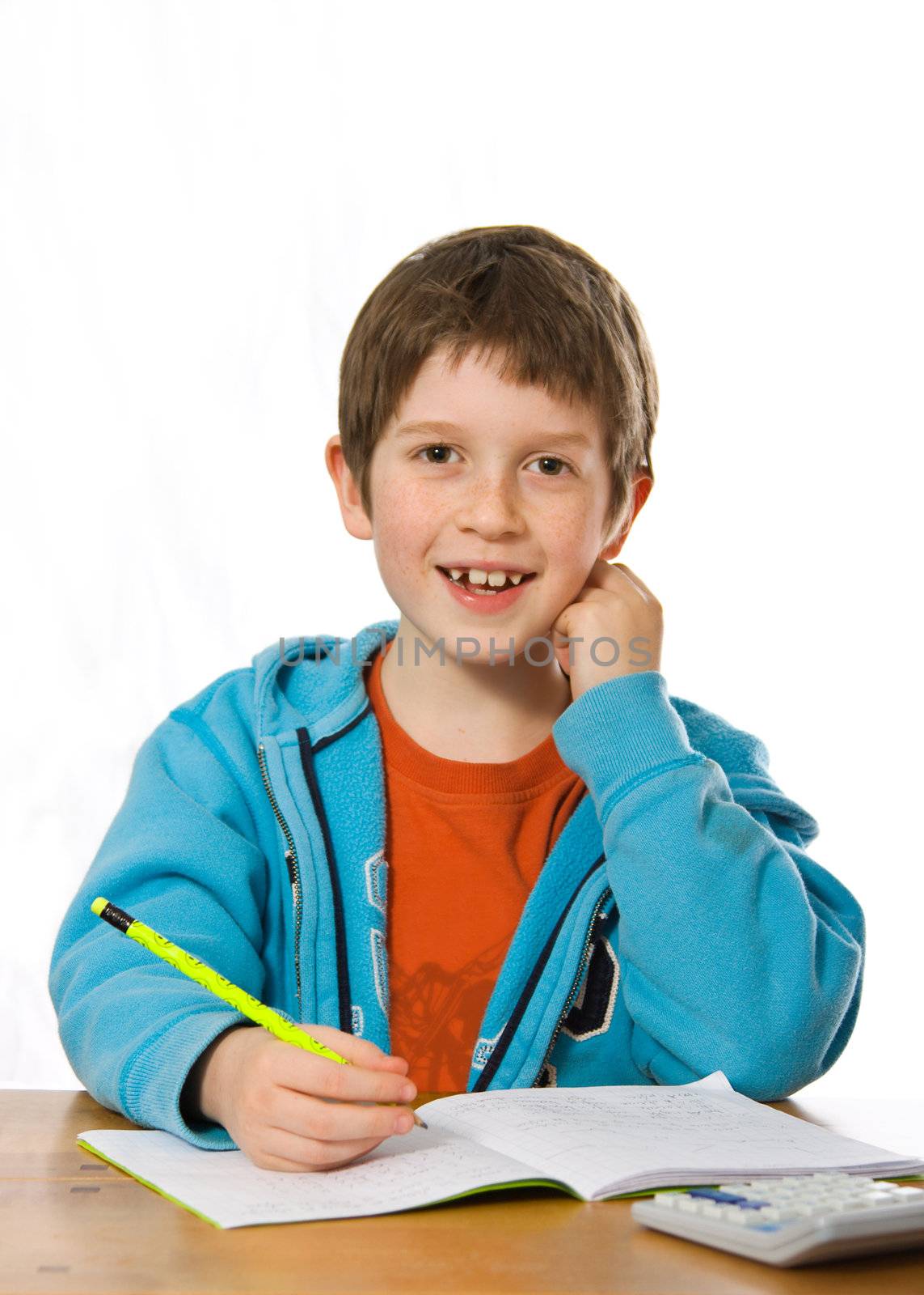 Happy young boy smiling whilst doing homework