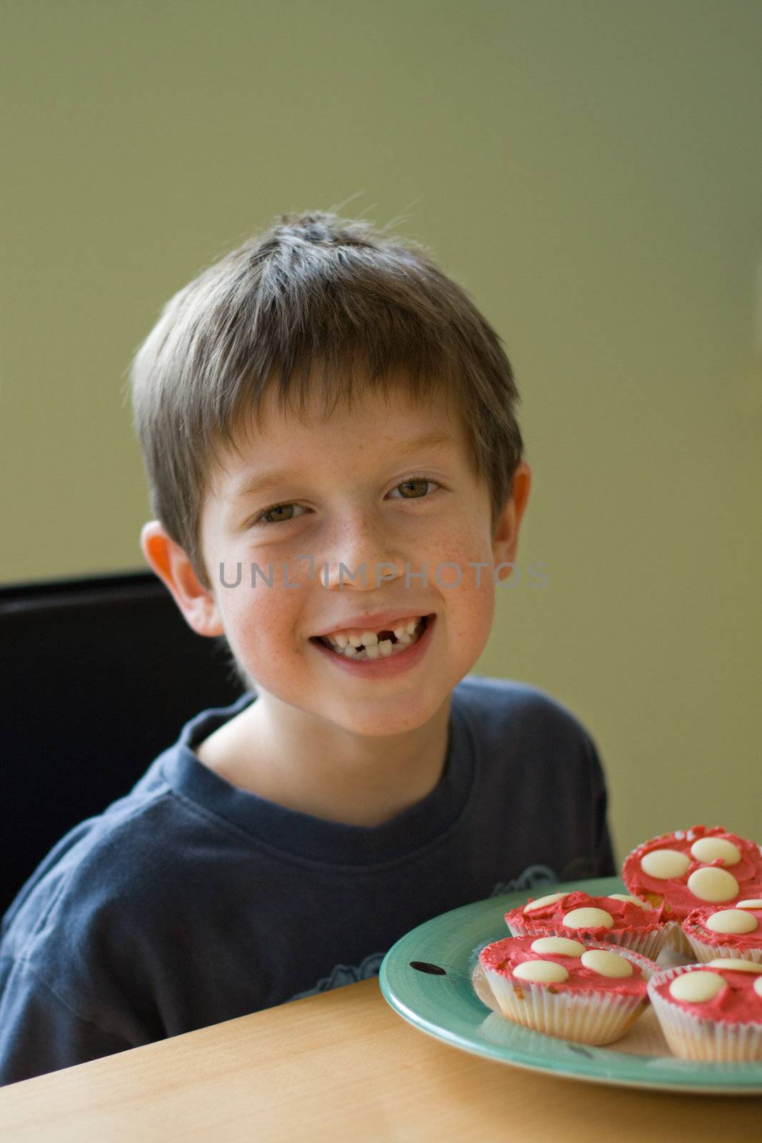 Boy with gap-tooth smile and cupcakes