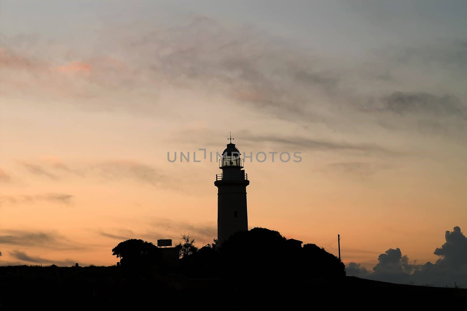 Lighthouse is silhouetted against a sunset
