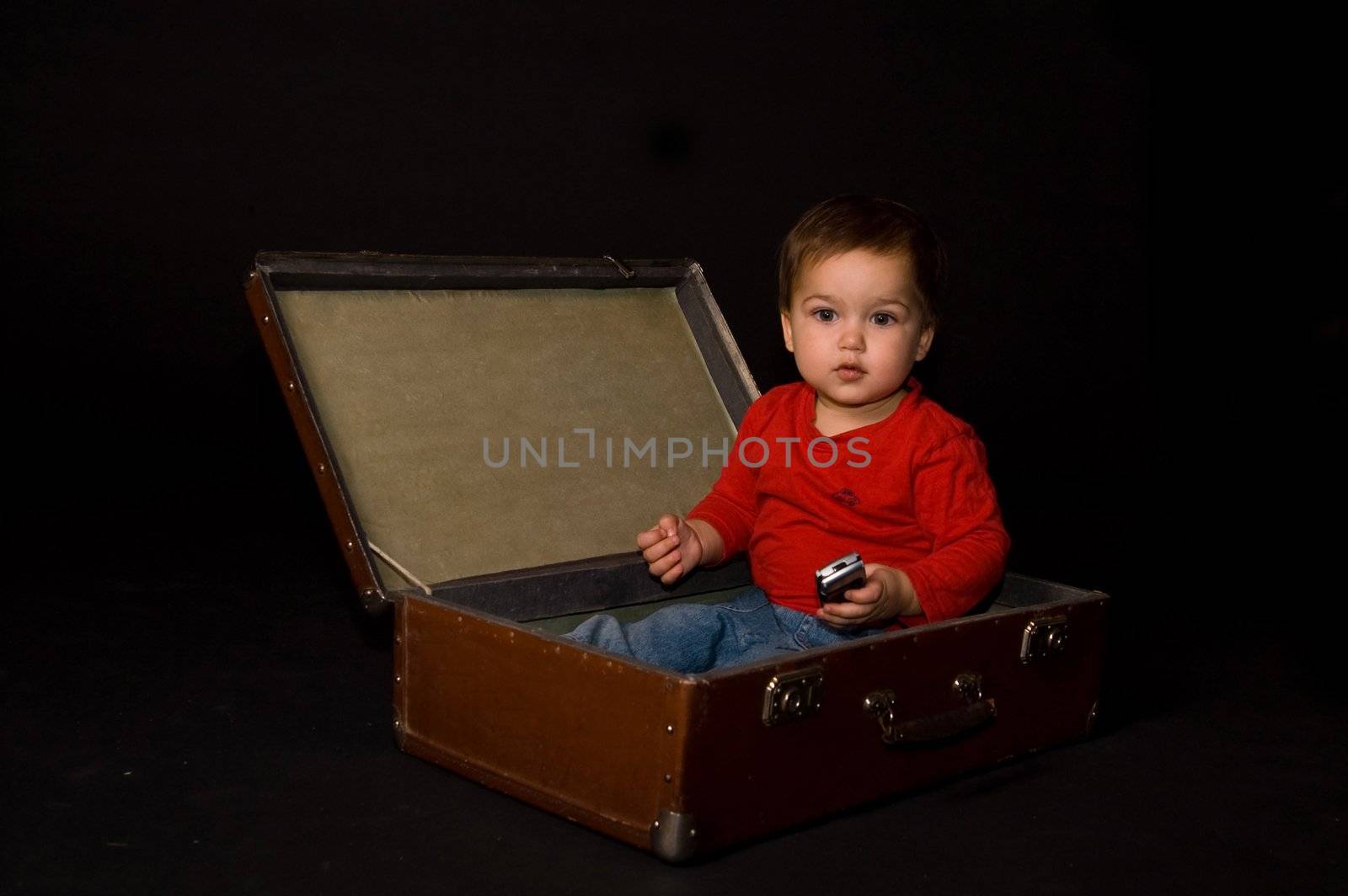 Surprised boy holding phone in luggage