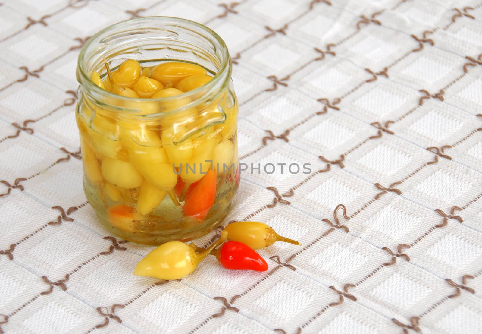 small yellow pickled hot peppers in opened jar on table