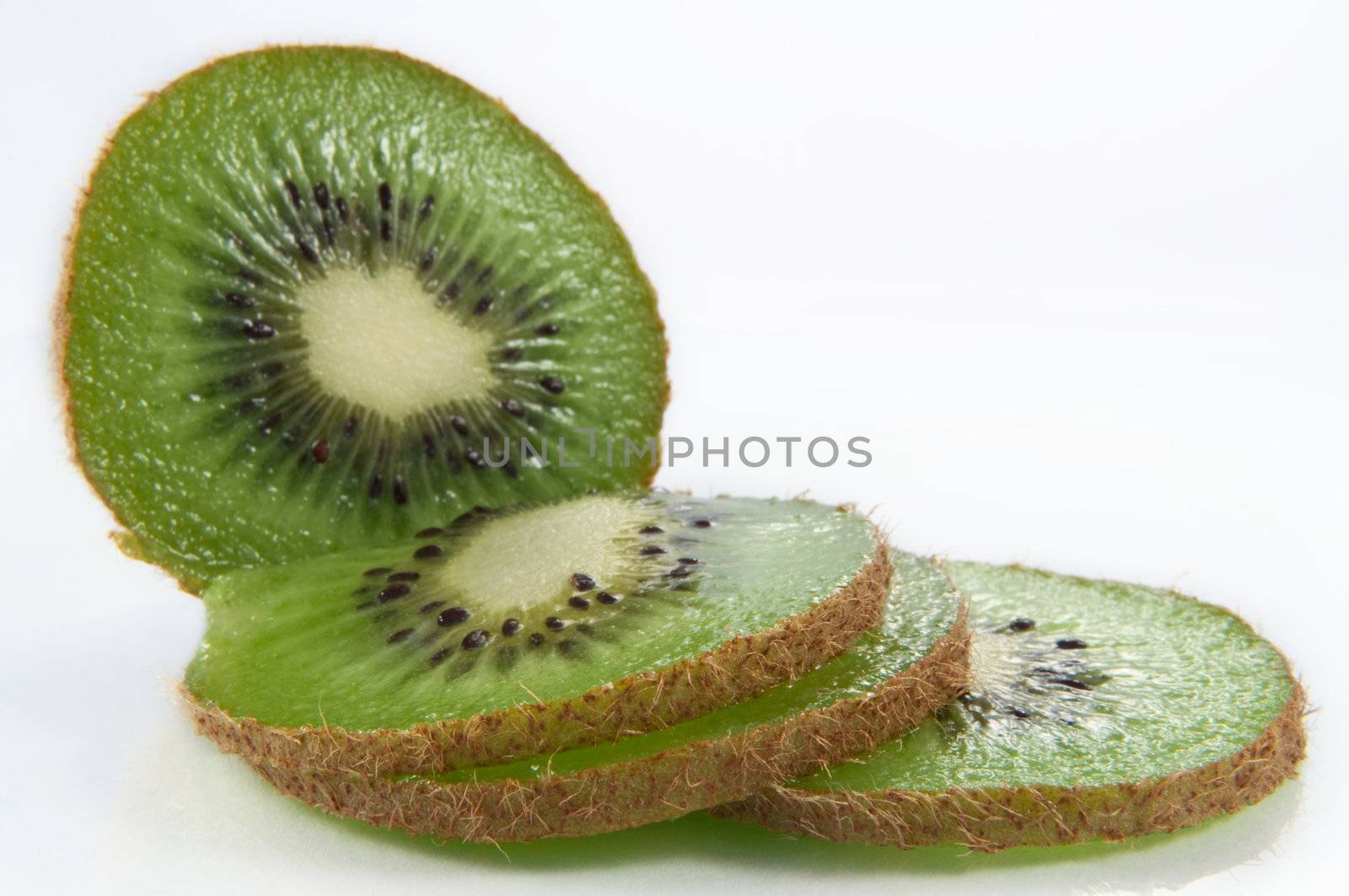 Close up and low level angle of a partially sliced fresh kiwifruit arranged over white.