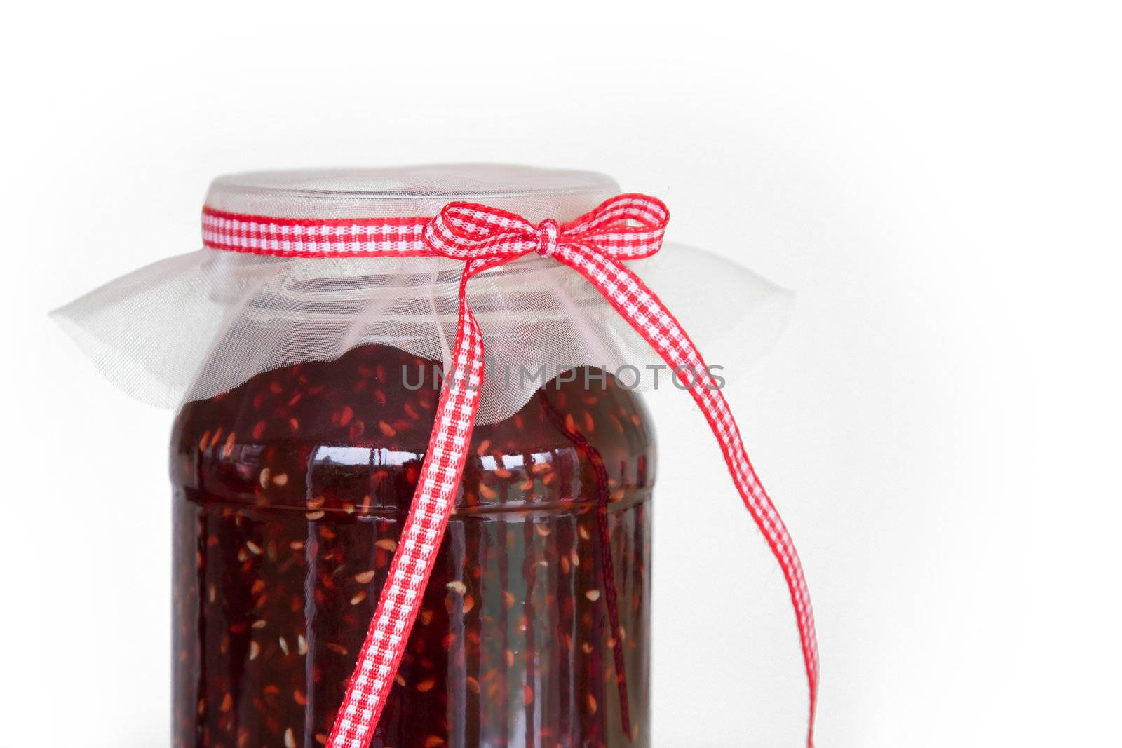 Jar of home made raspberry jam tied with a gingham ribbon