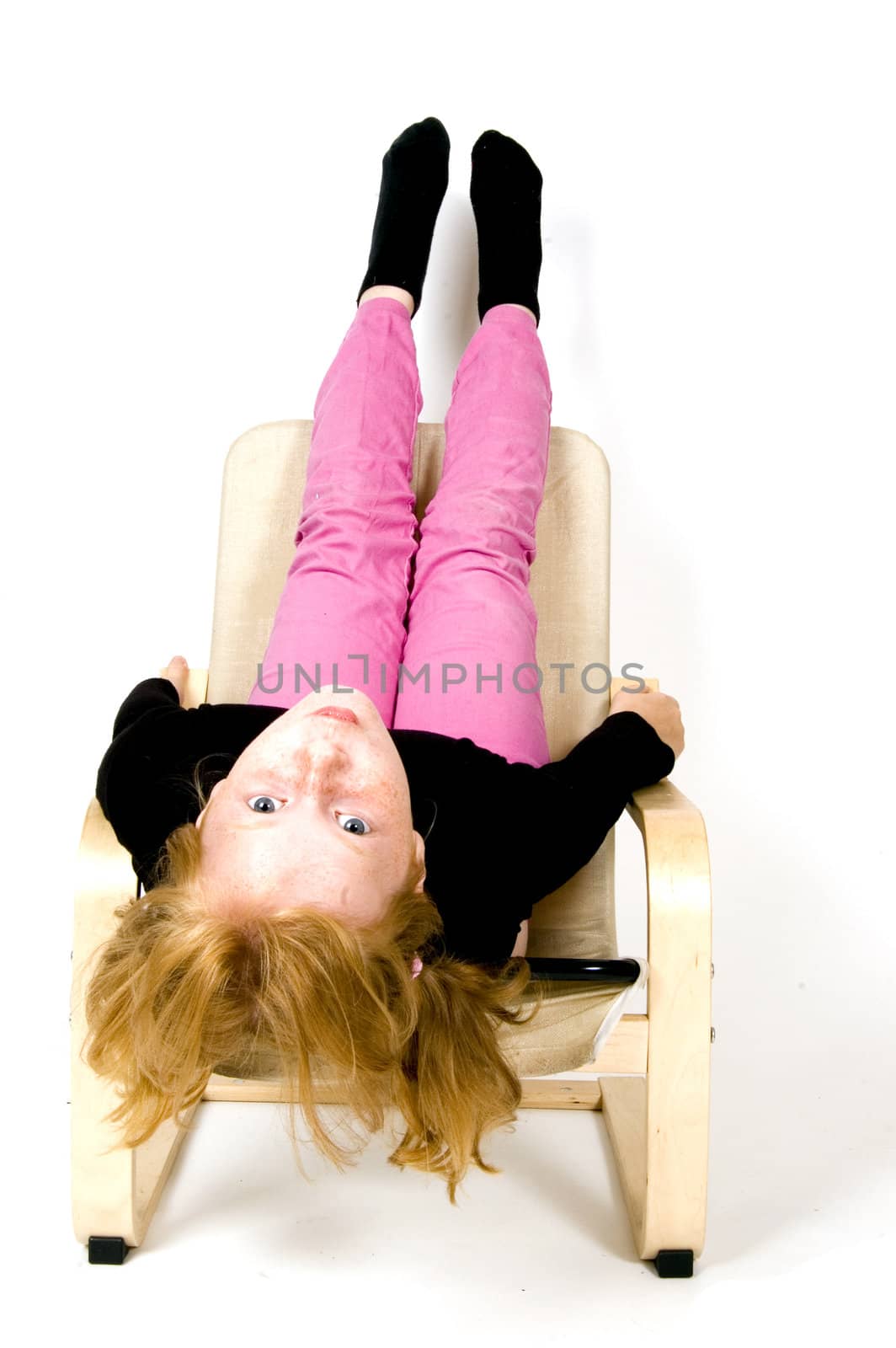 little girl is hanging upsite down on a chair