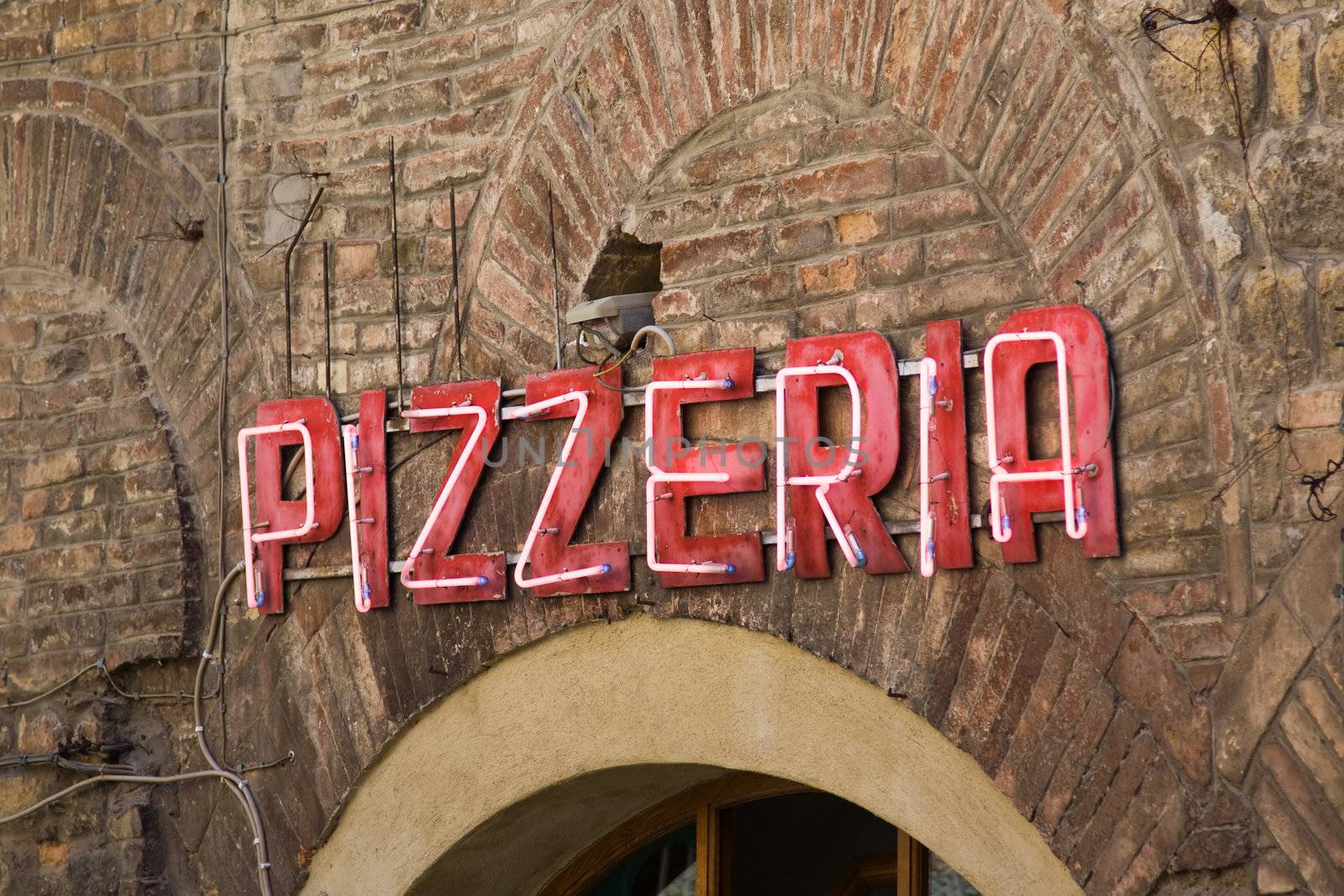 Pink neon pizzeria sign outside an Italian restaurant