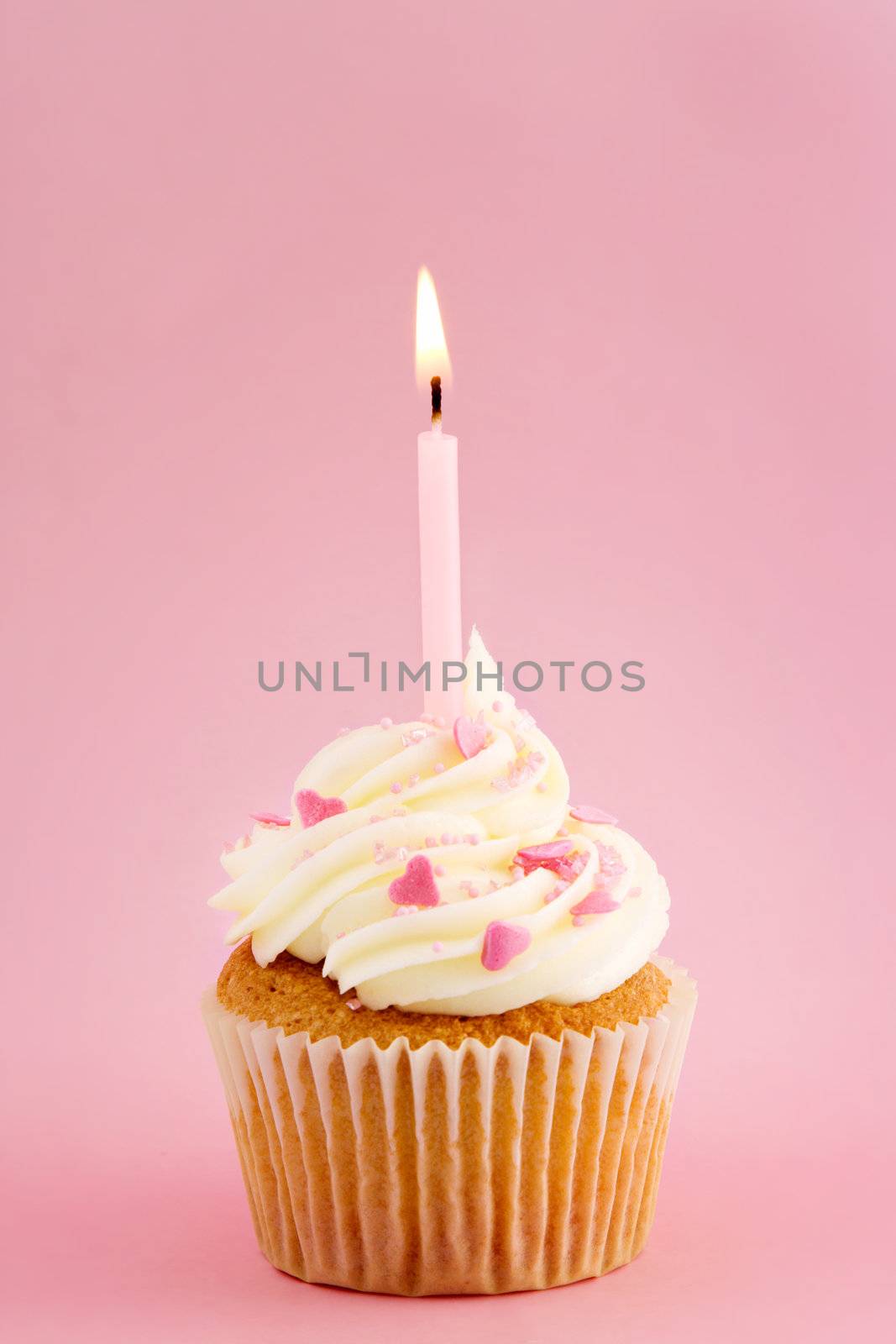 Cupcake decorated with pink sprinkles and a single candle