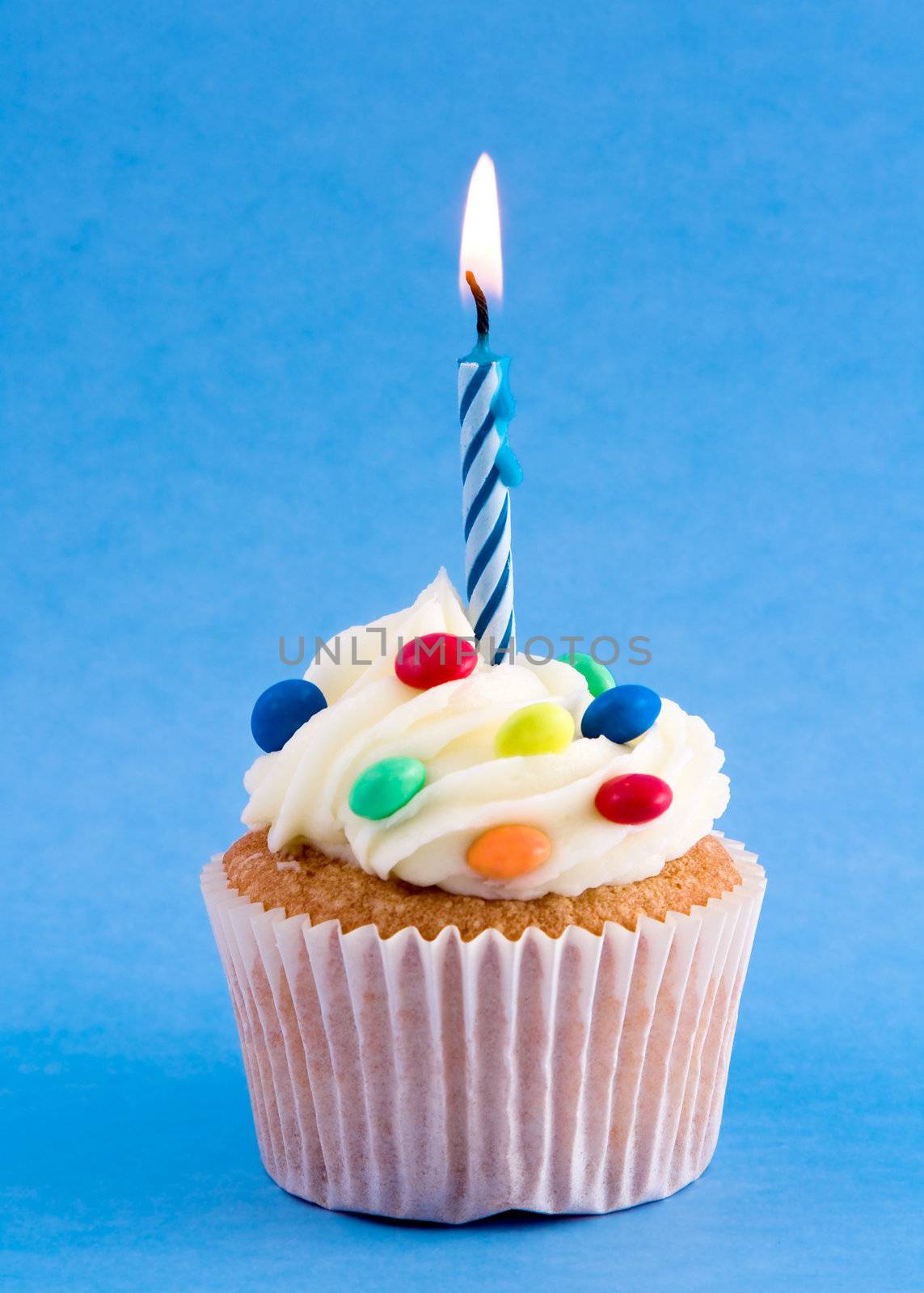 Birthday cupcake decorated with candy and a single candle