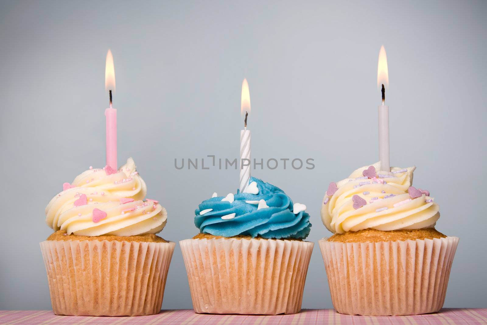 Trio of cupcakes decorated with frosting and candles