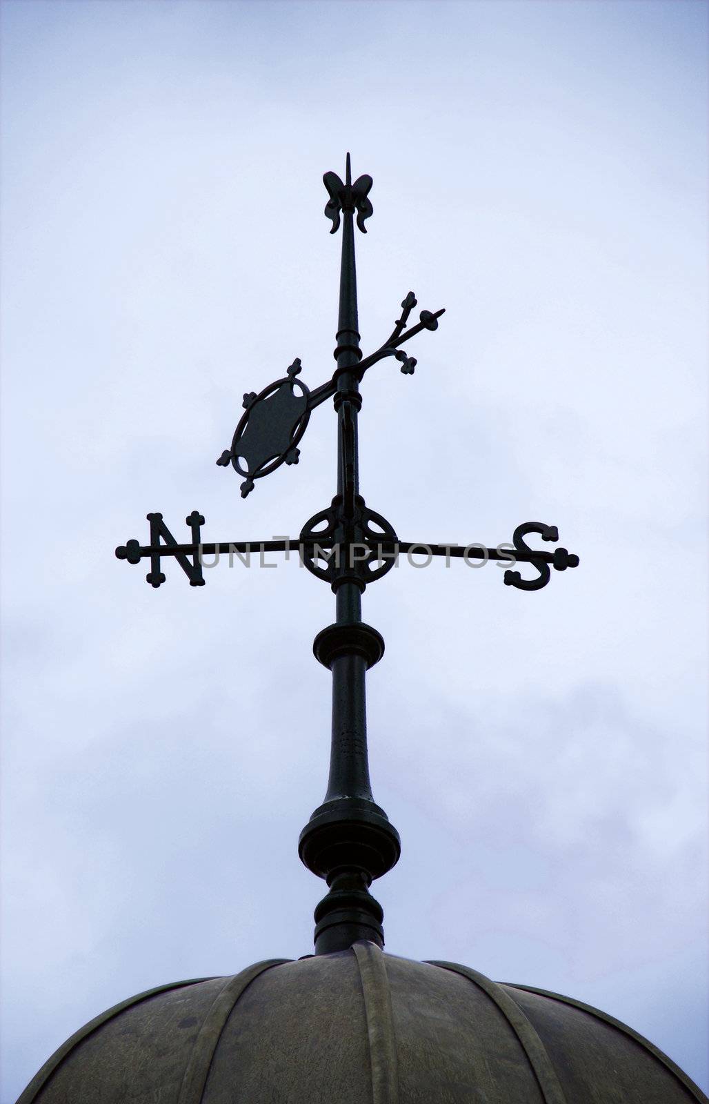 A photograph of the north and south points of the compass and the wind direction indicated by an arrow on a traditional weather vane