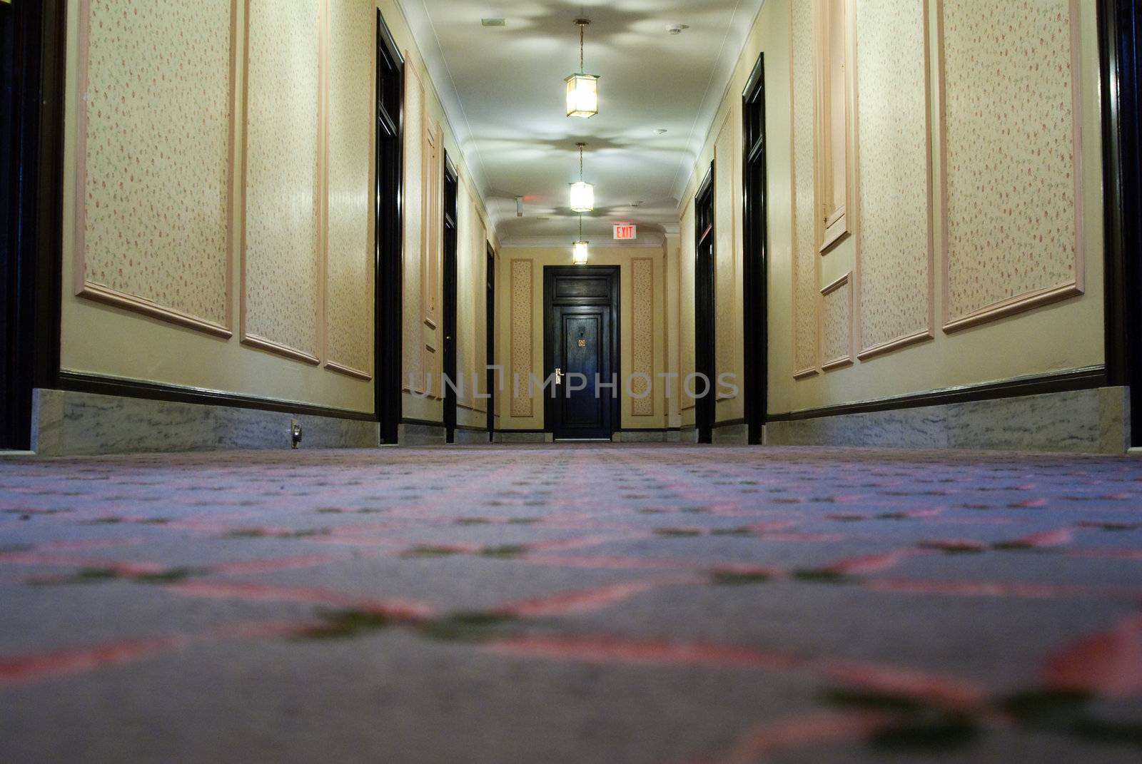 Low angle view of a hotel hallway with a doors on the side and at the end.