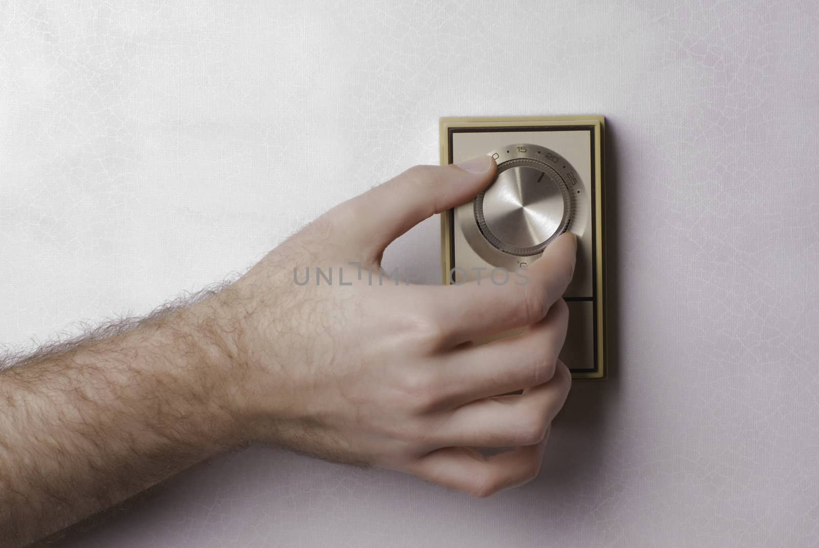 Closeup view of a hand turning down an old home thermostat