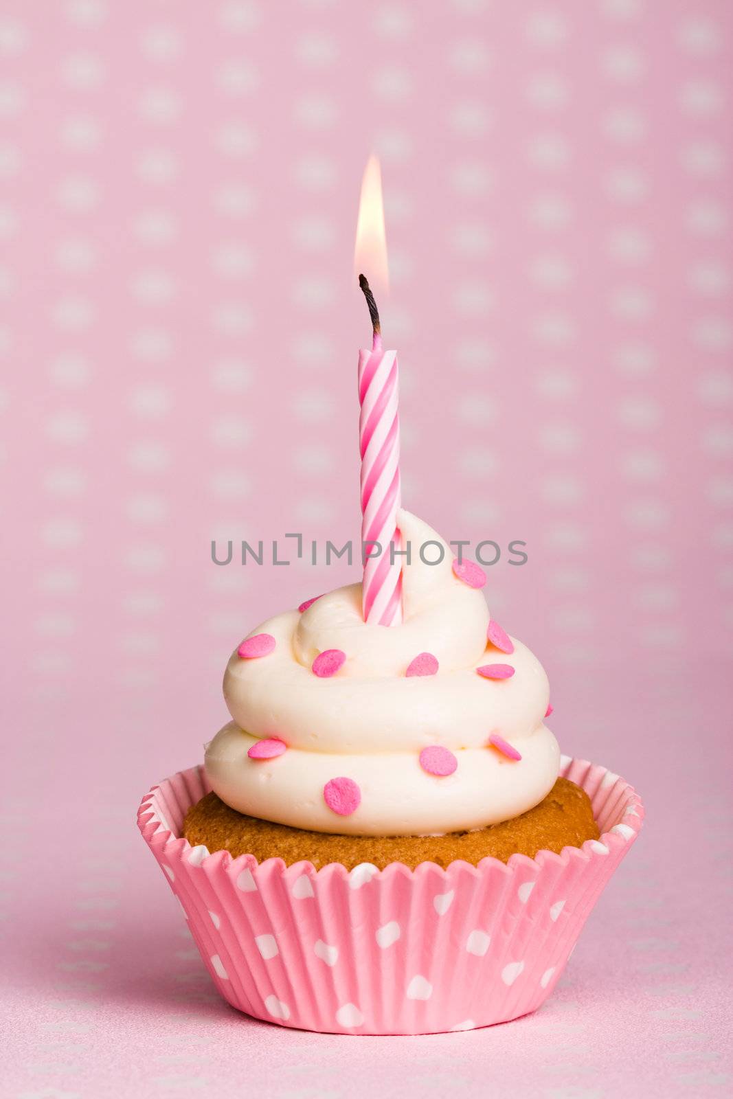 Spotty pink cupcake with a stripey candle