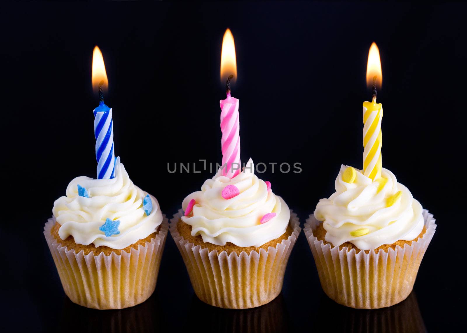 Trio of birthday cupcakes against black