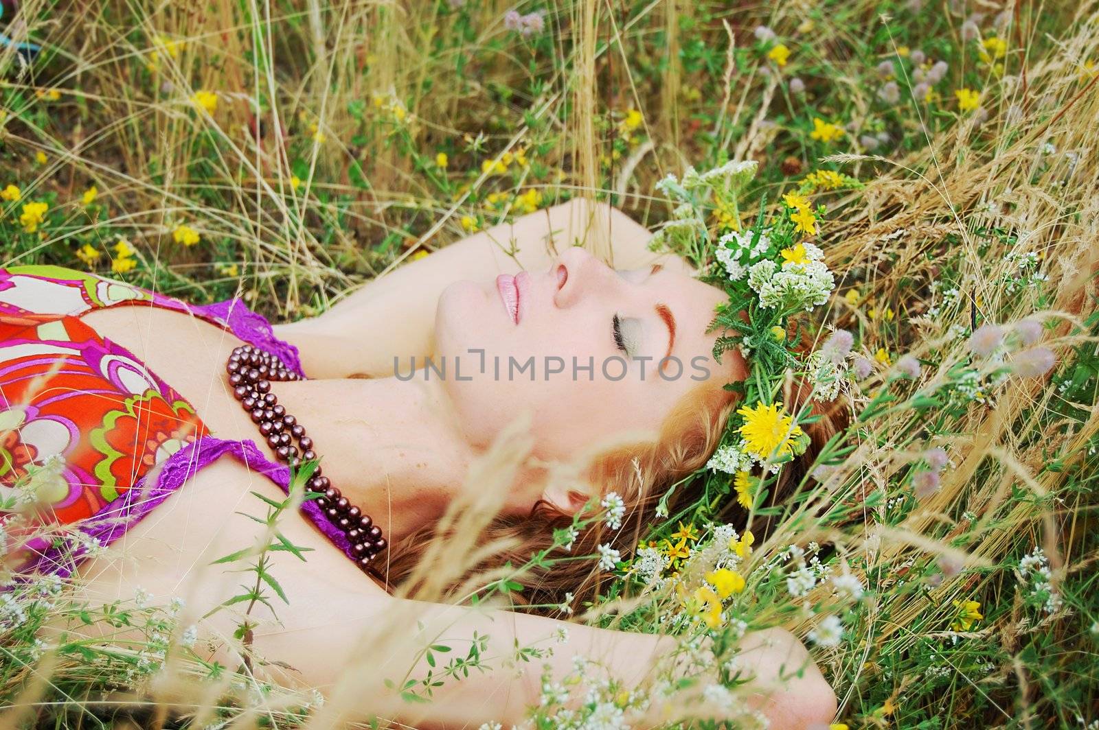 Beautiful girl with flower diadem lying in grass