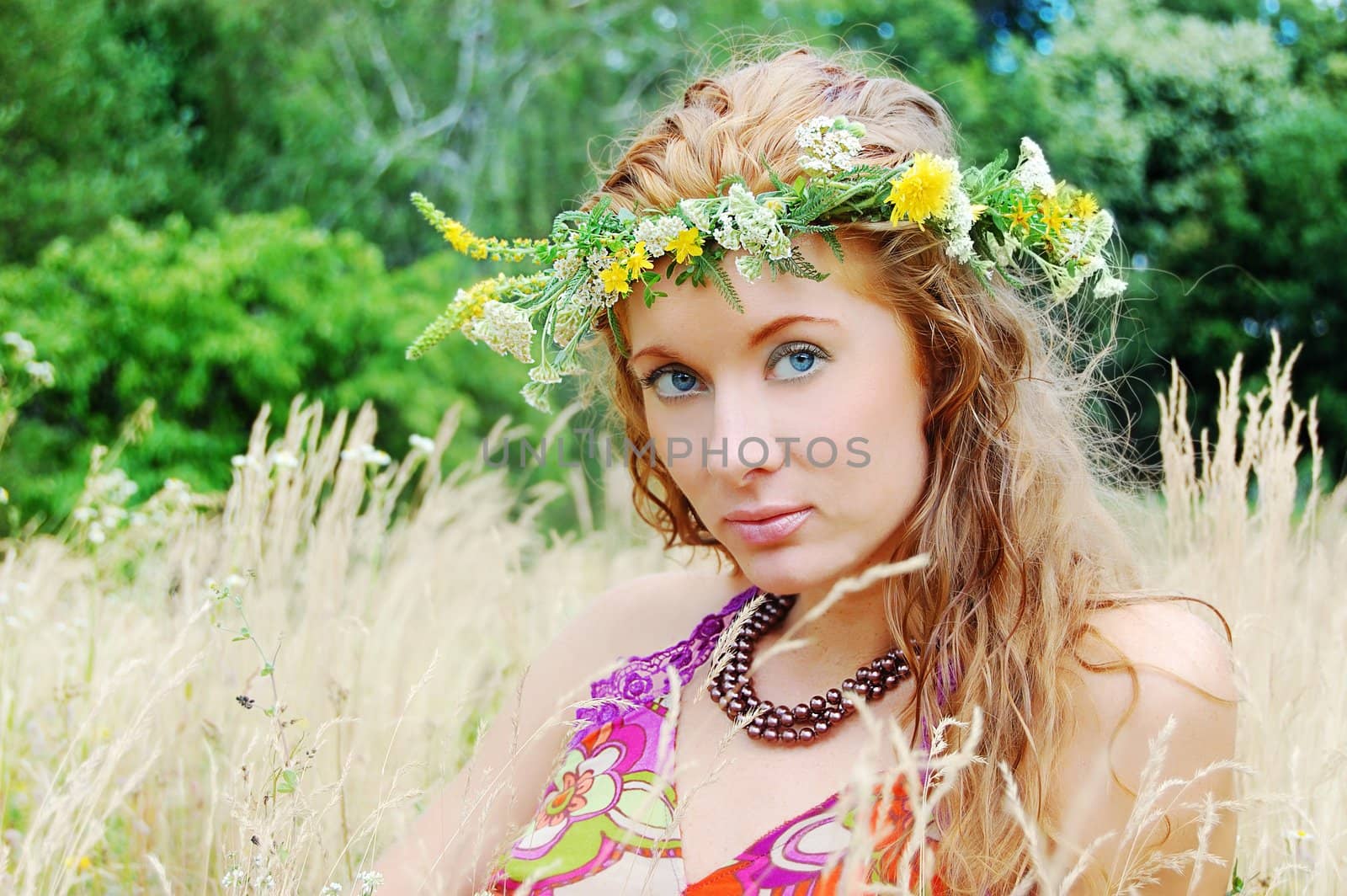 Beautiful girl with flower diadem among fields