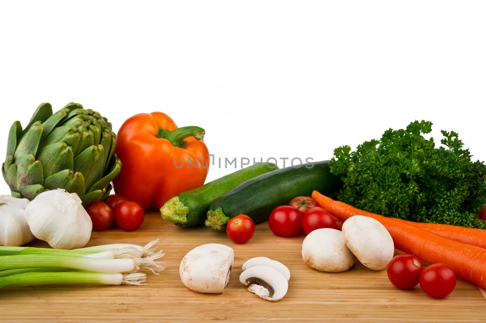 Image of a wood cutting board with assorted vegetables on a white background