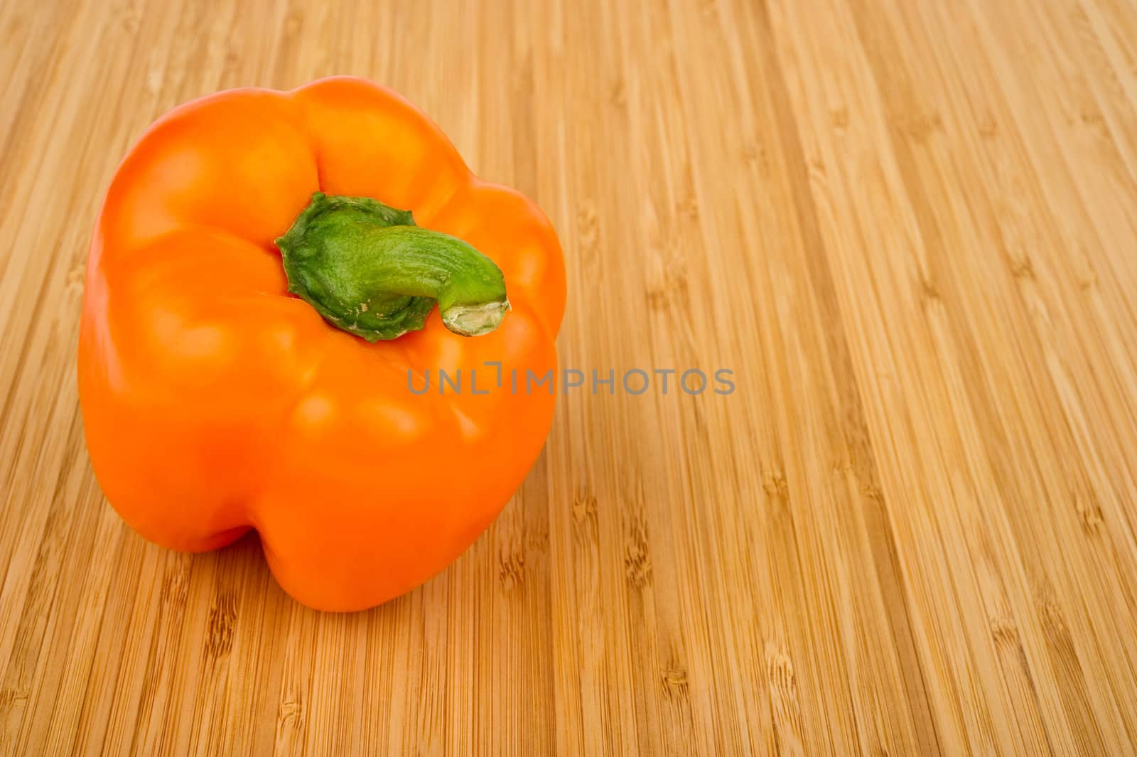 Image of an orange bell pepper on a wooden cutting board