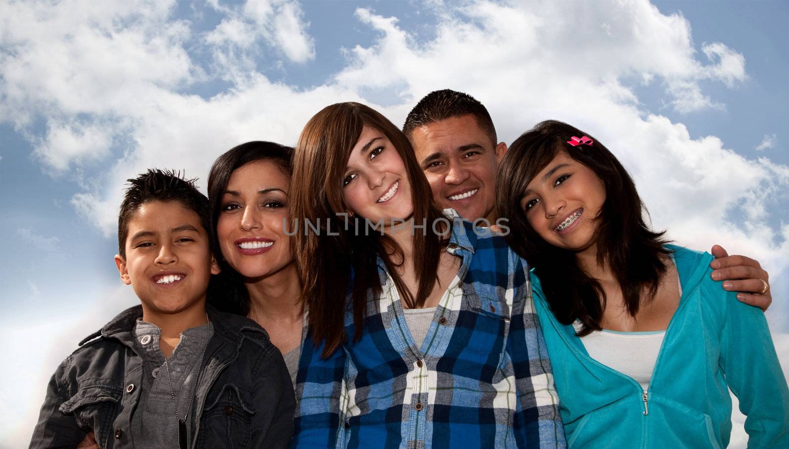 Hispanic family seated against a cloudy sky