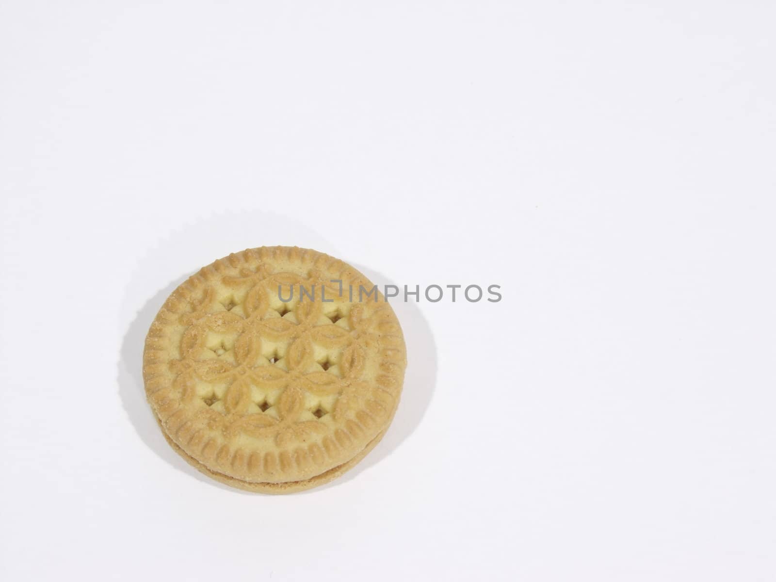 Single vanilla cookie lying on a white surface