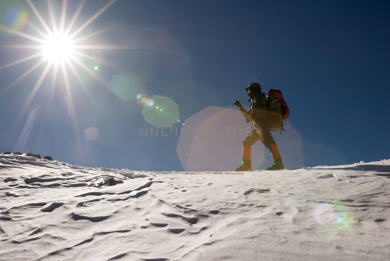 Man of mountain climber walk in snow winter day with sun light flare.