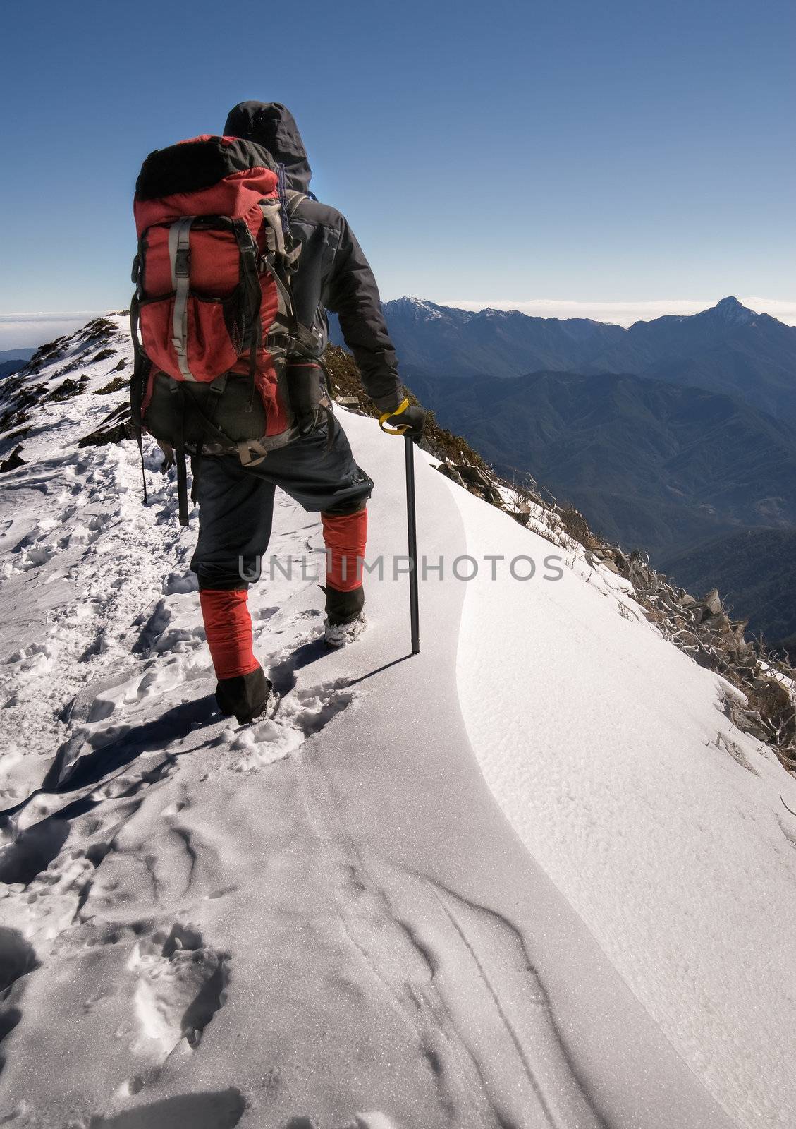 Single man of climber walk alone on top of snow ice winter mountain.