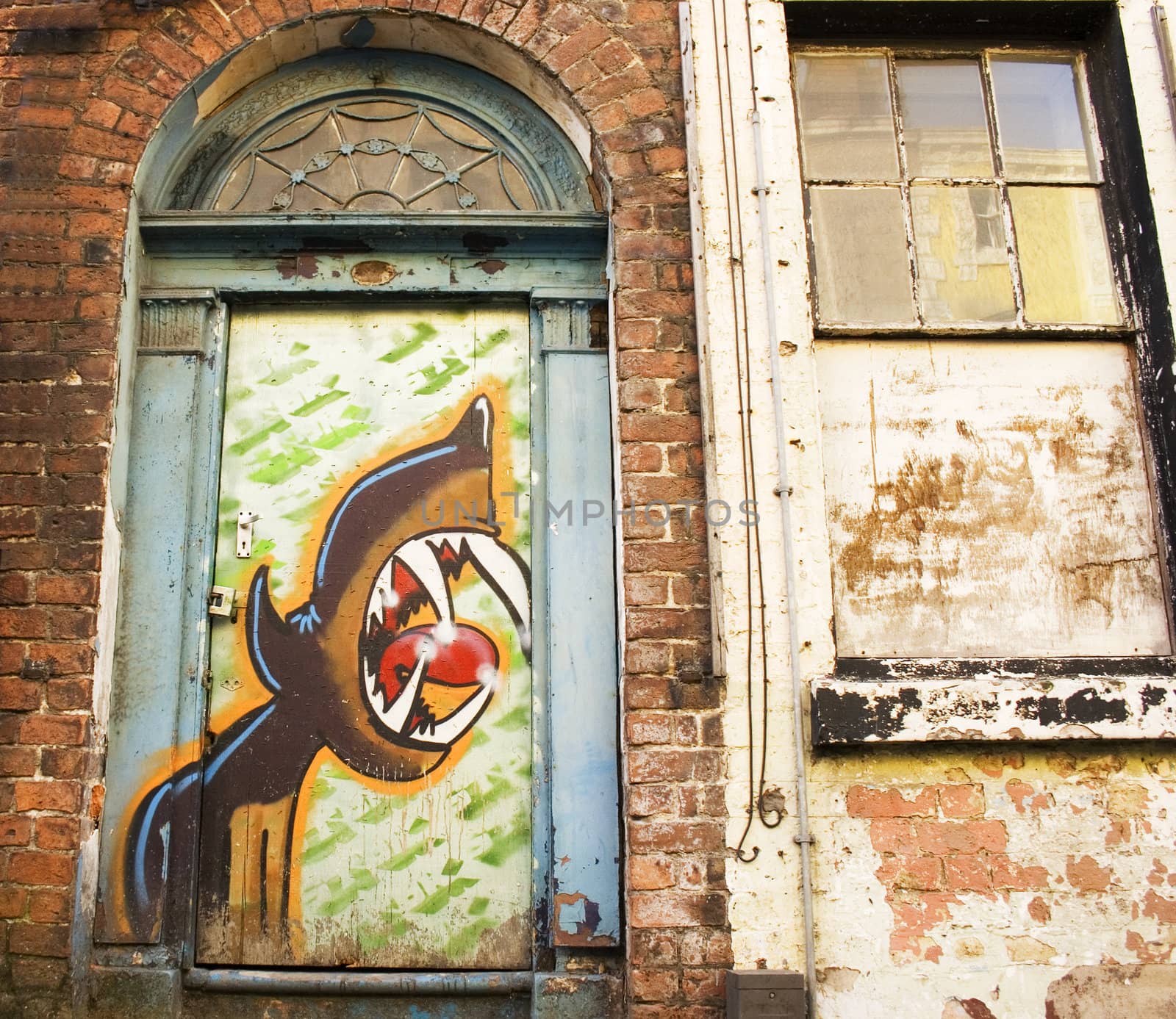 Arched derelict doorway covered in graffiti
