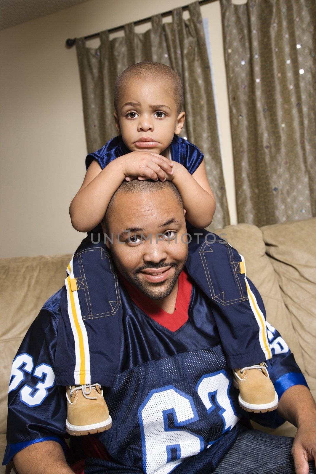 Portrait of African-American father with his son on his shoulders.