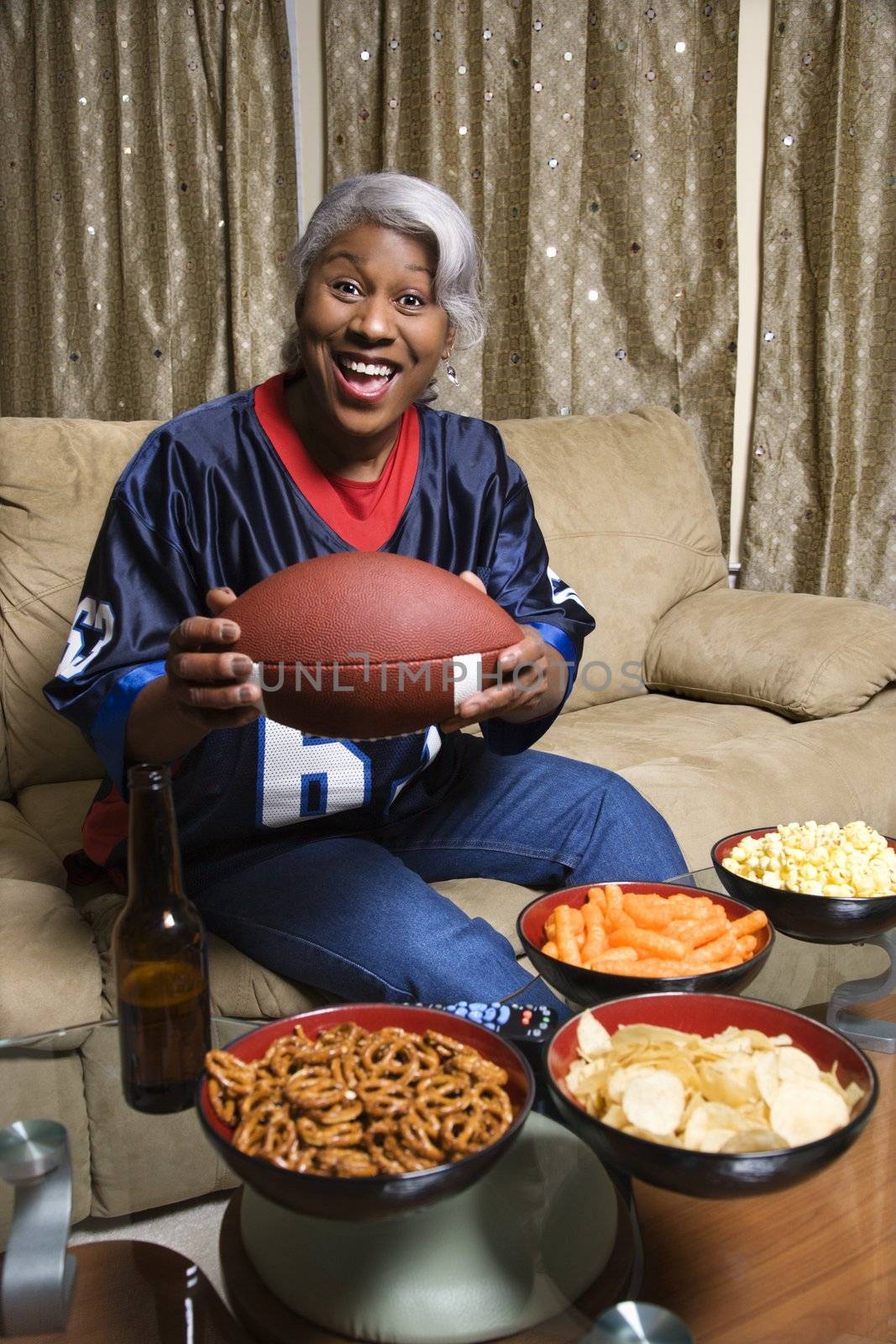 Portrait of smiling Middle-aged African-American woman wearing jersey and holding football.