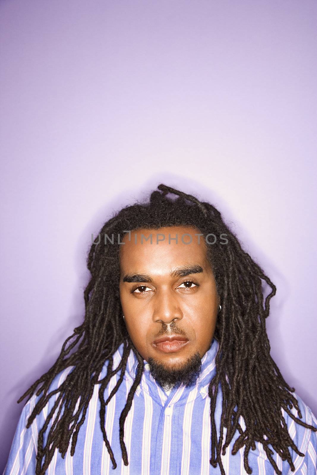 Serious African-American mid-adult man on purple background.