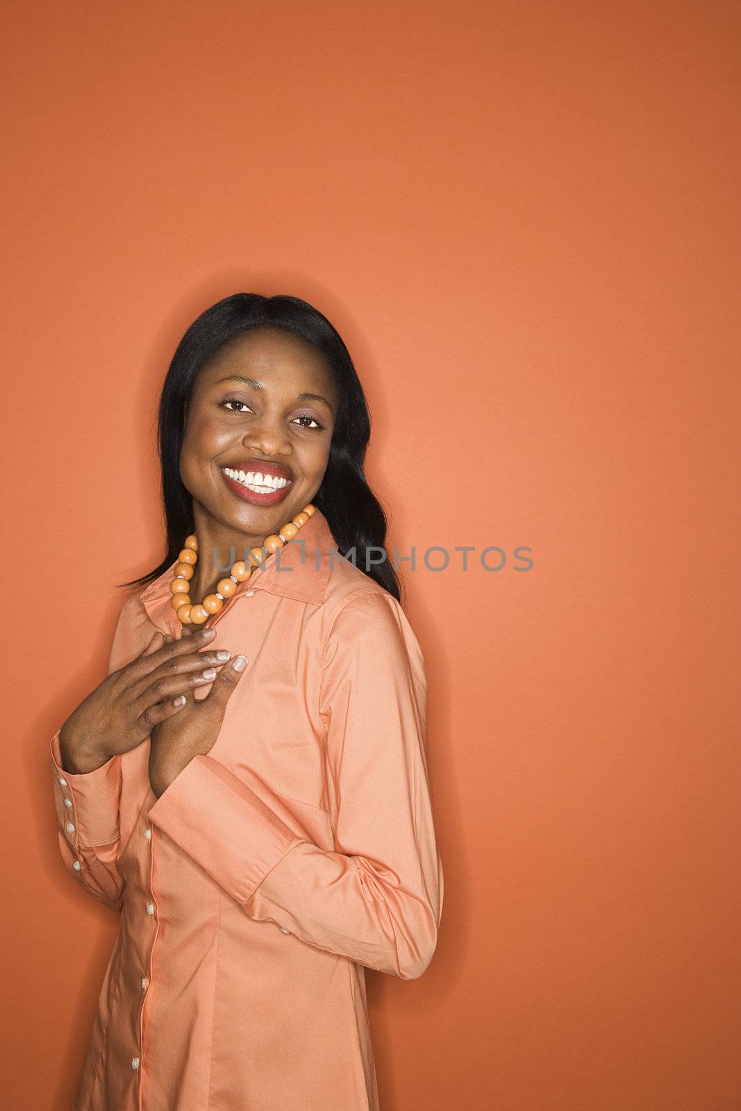 African-American mid-adult woman on orange background wearing orange clothing.