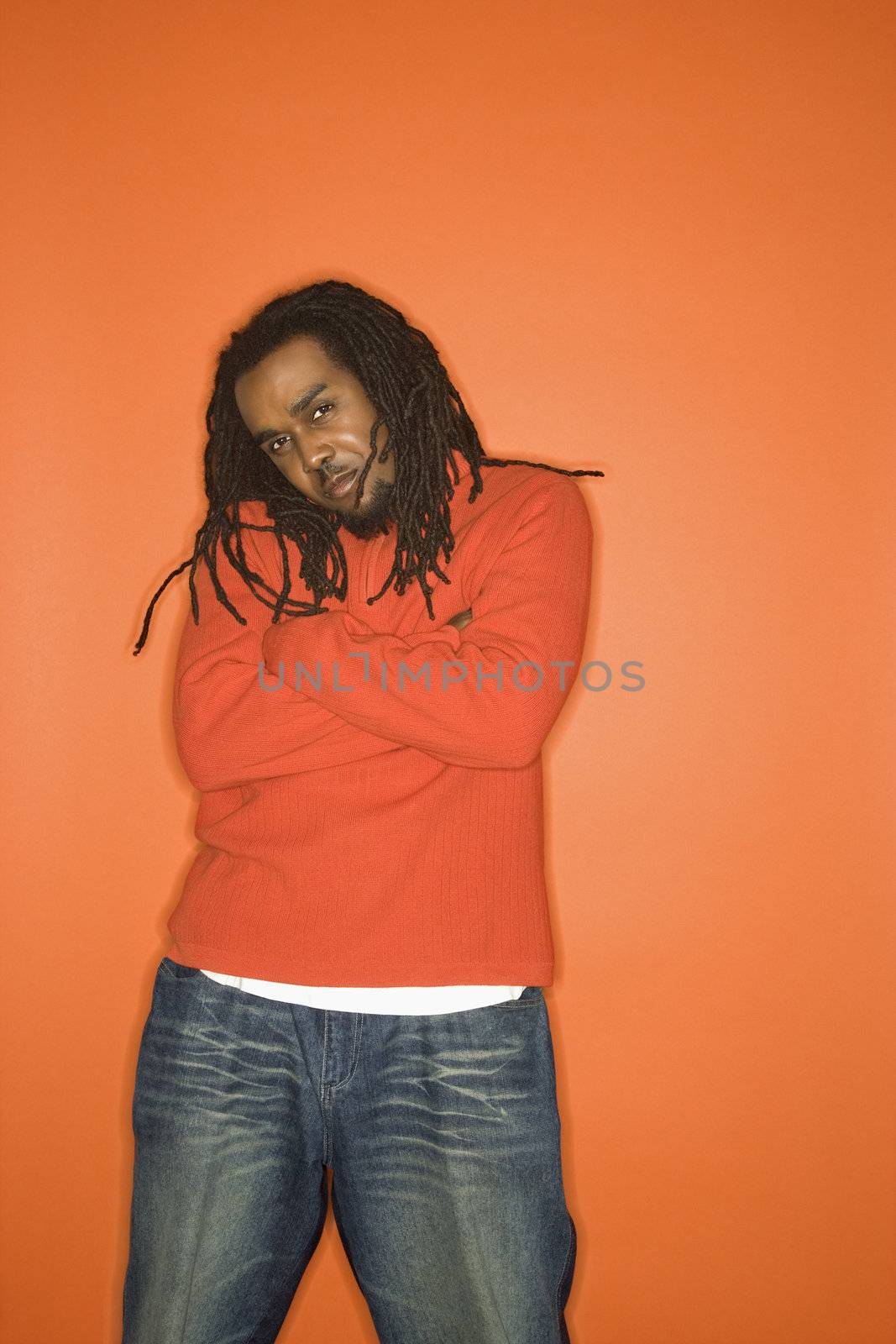 African-American mid-adult man with crossed arms and attitude wearing orange clothing on orange background.