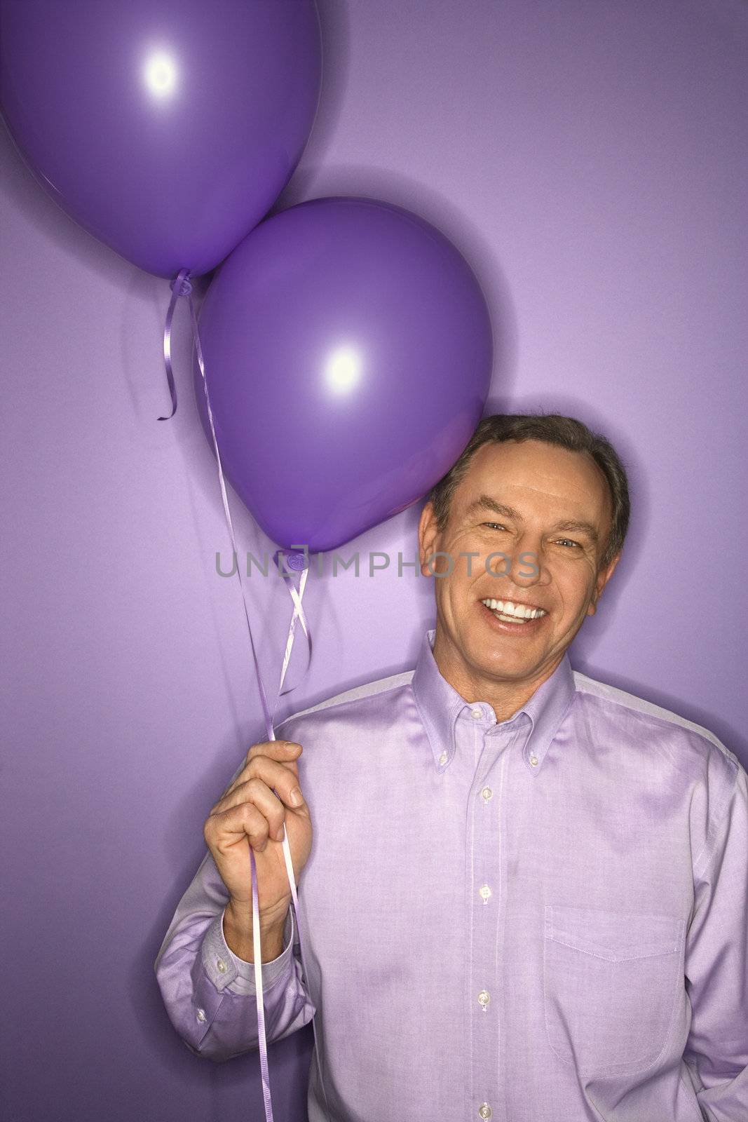 Man holding balloons. by iofoto