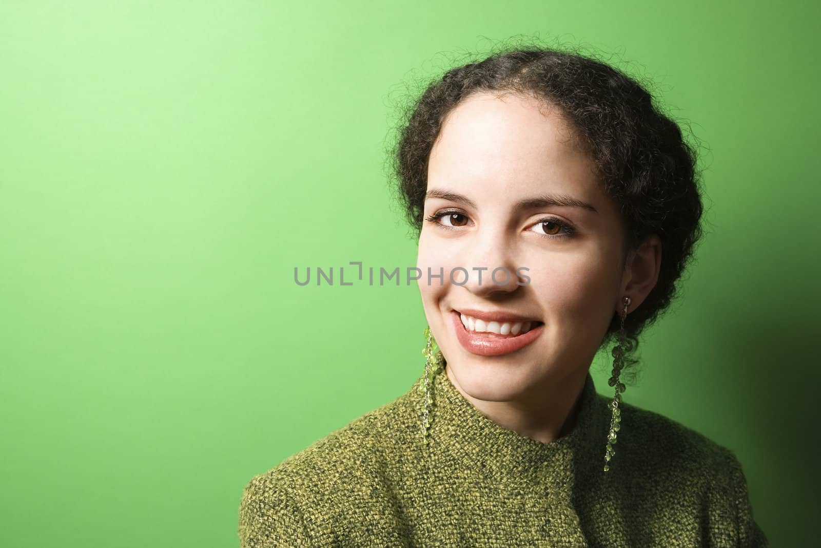 Smiling young Caucasian woman on green background wearing green clothing.