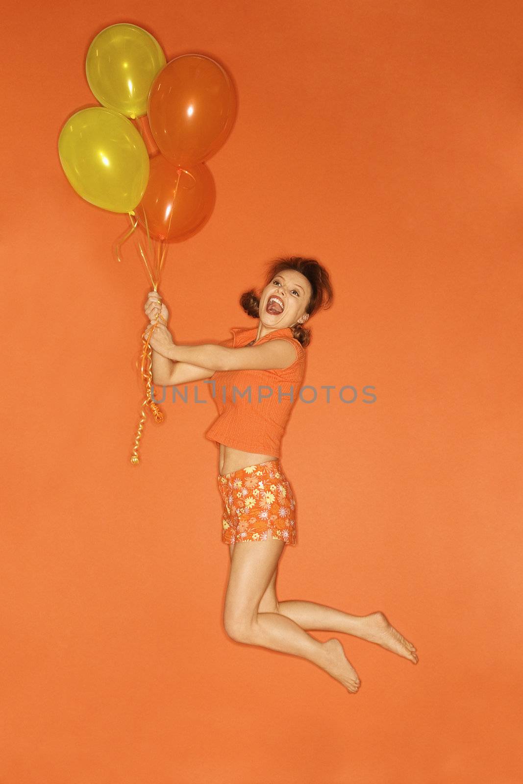 Woman lifted by balloons. by iofoto