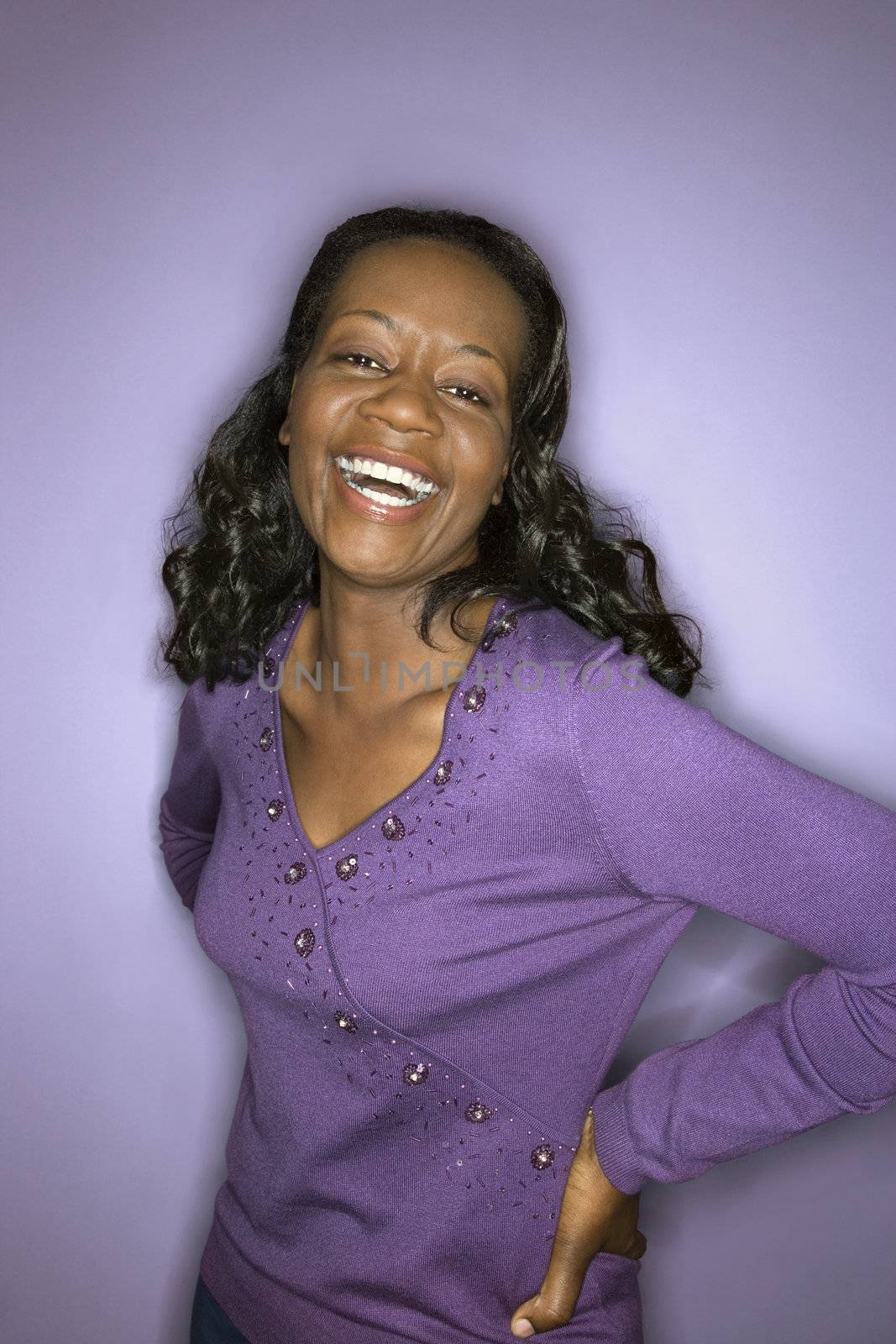 Portrait of laughing mid-adult African-American woman on purple background.
